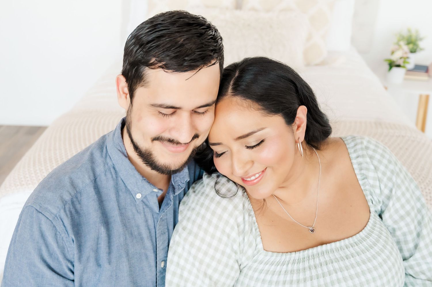 Intimate close-up portrait of couple in blue and gingham outfits with gentle expressions.