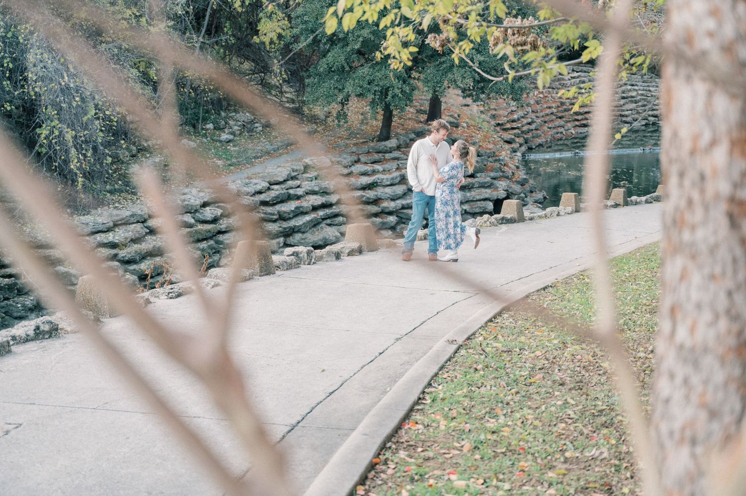 A romantic scene unfolds on garden steps with trees and fallen leaves creating a natural backdrop.