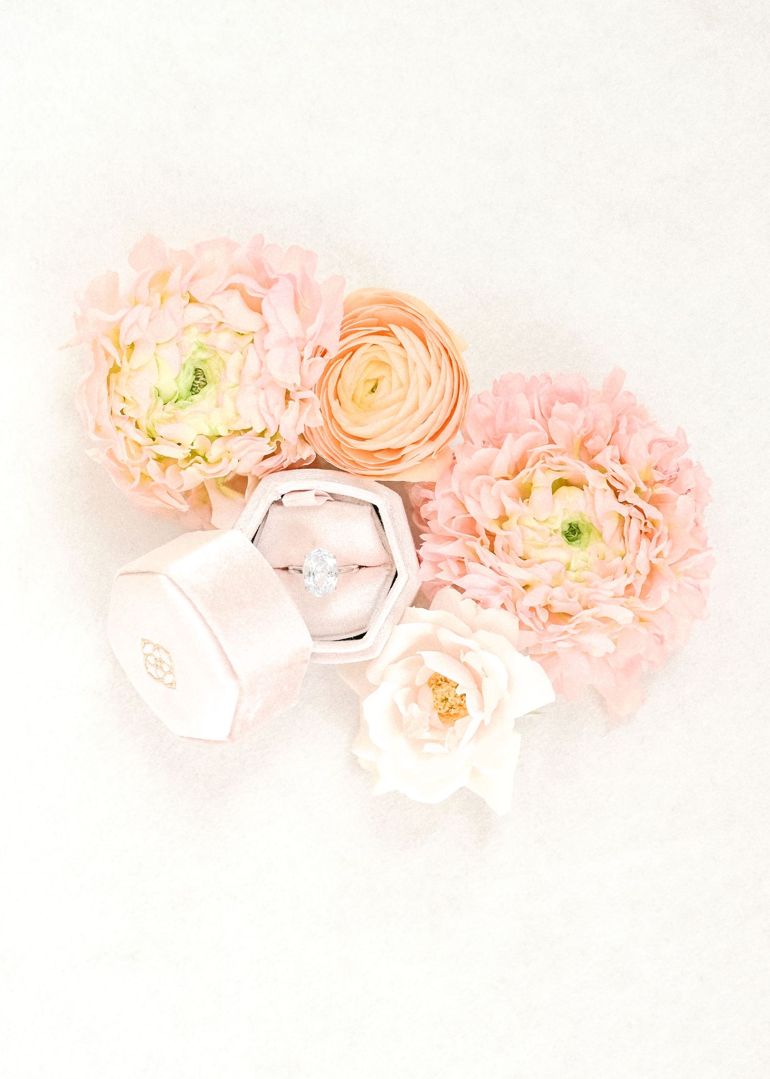 Soft pink ranunculus and roses arranged with geometric decor elements.