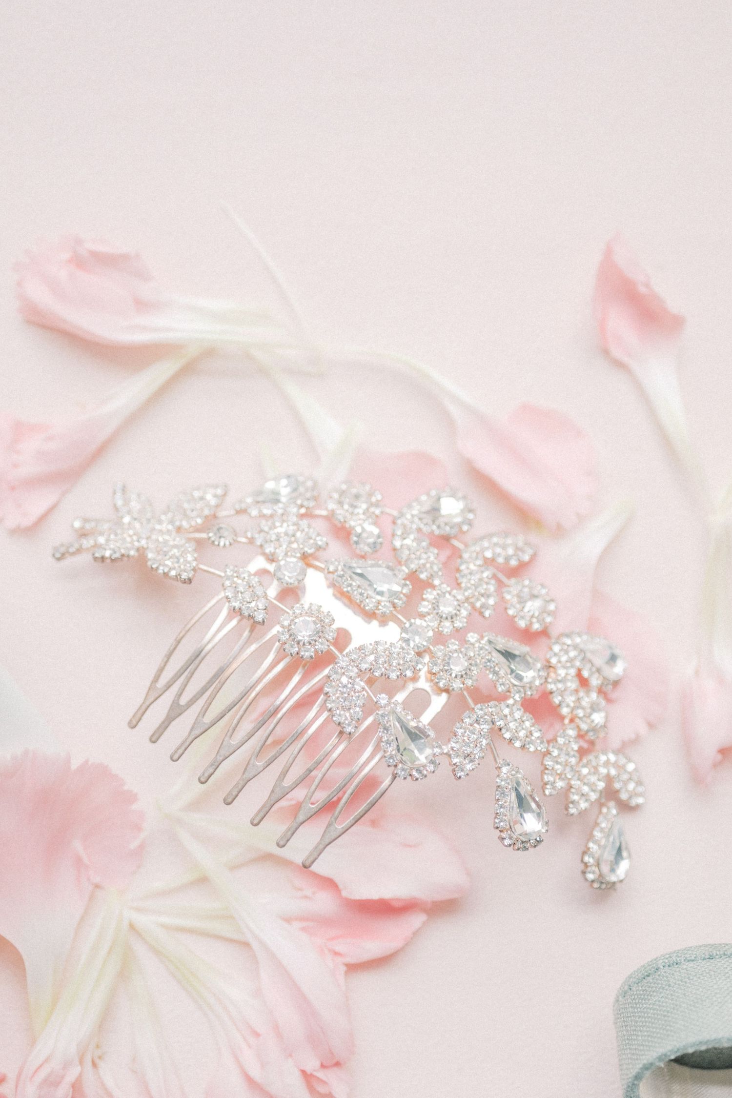 Silver crystal floral bridal hair comb with rhinestones on pink background with rose petals.