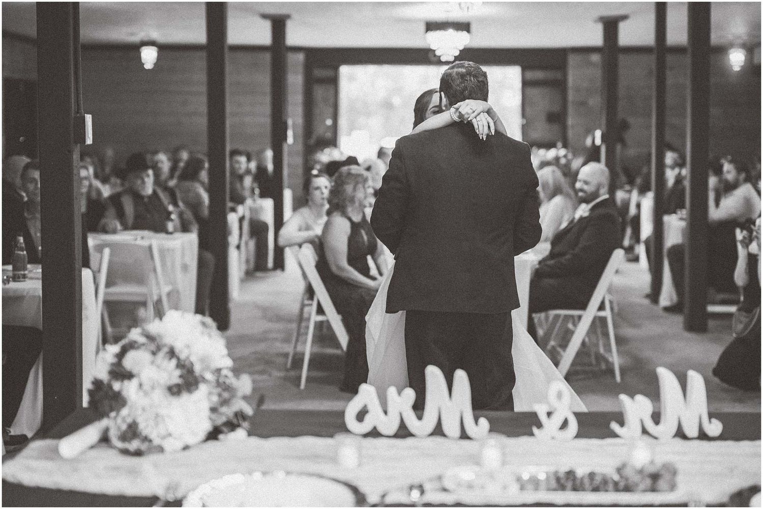 Black and white photo of a wedding ceremony in a classic indoor venue with columns.