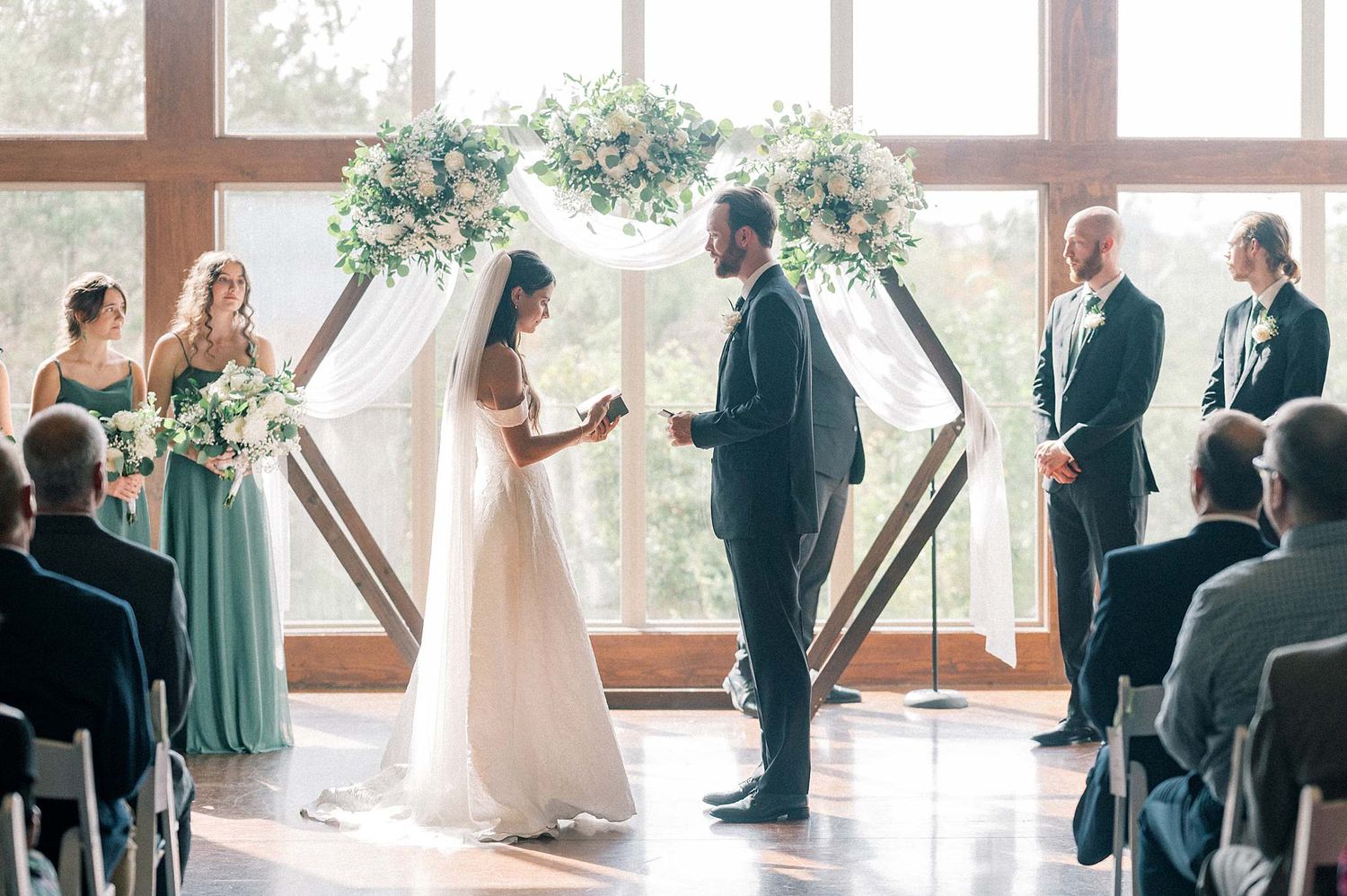 Indoor wedding ceremony setup with wooden beams and natural light streaming through windows.
