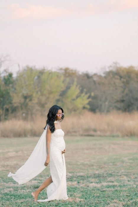 Dreamy portrait session in a field shows flowing white fabric catching the breeze.