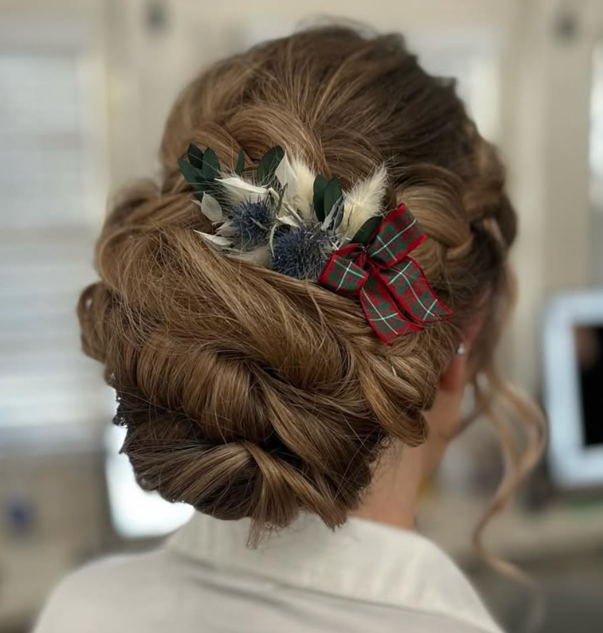 Elegant bridal updo with tartan bow and dried flower hair accessories, showcasing a twisted chignon hairstyle.