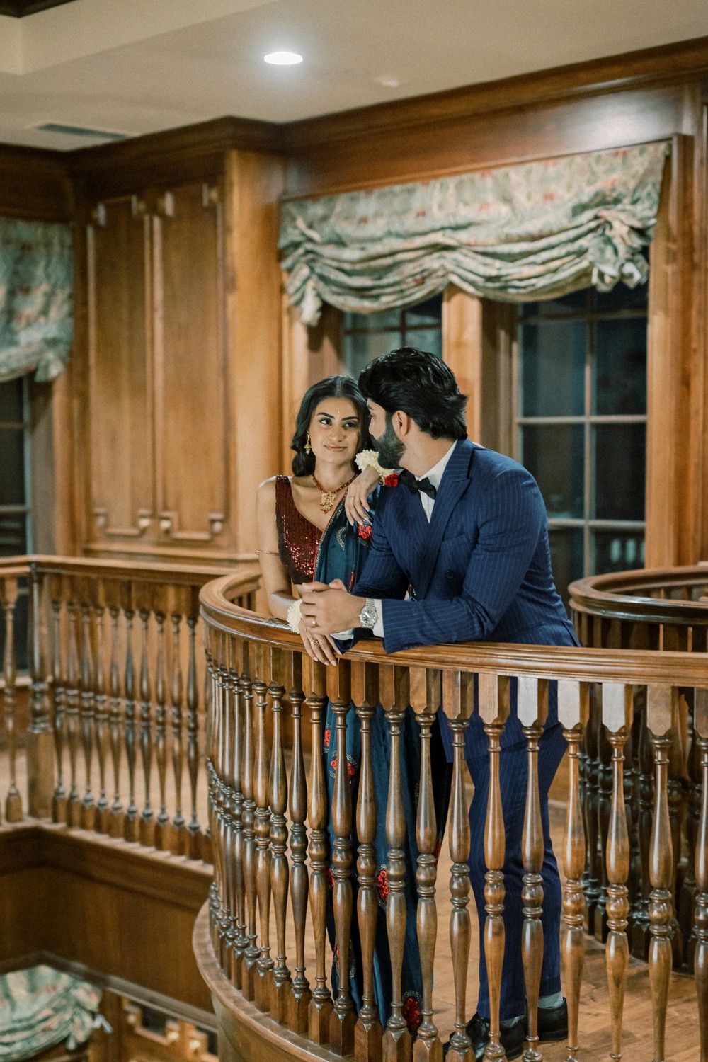 Couple sharing intimate moment on wooden balcony with classic architectural details.