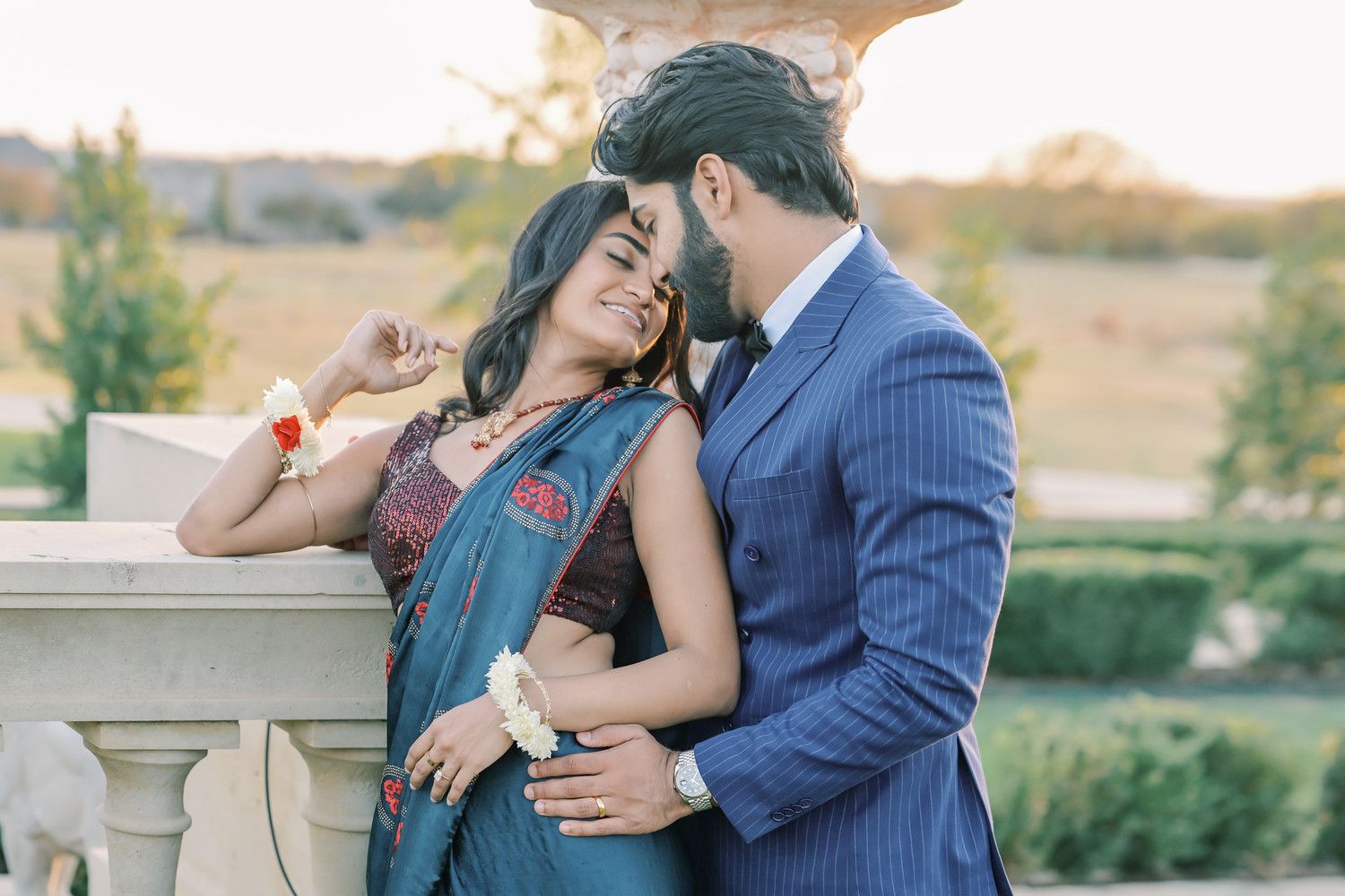 Intimate moment between couple in traditional formal wear against sunset backdrop.