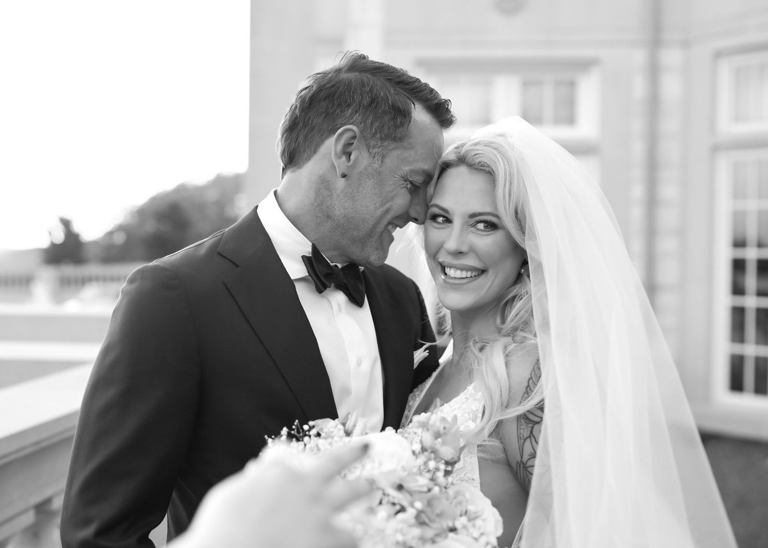 Black and white candid wedding portrait showing joyful couple in formal attire.