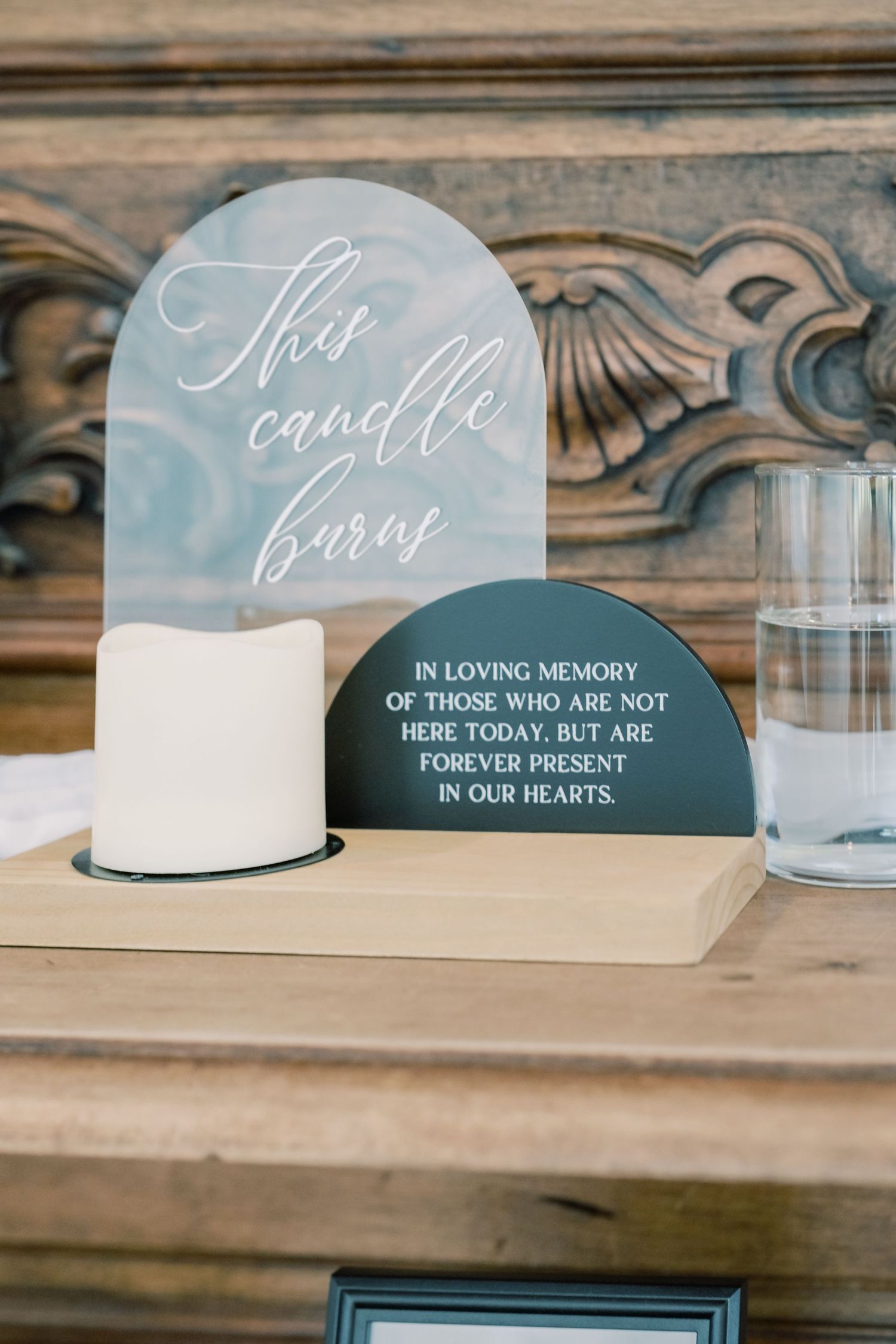 Memorial candle display with acrylic sign honoring absent loved ones at wedding reception.