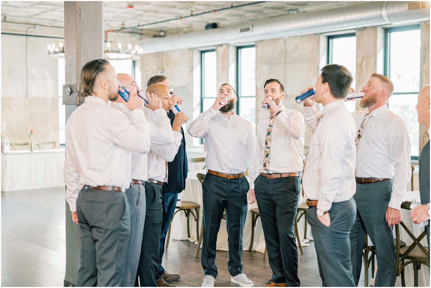 Wedding party groomsmen adjusting ties and suits before ceremony.