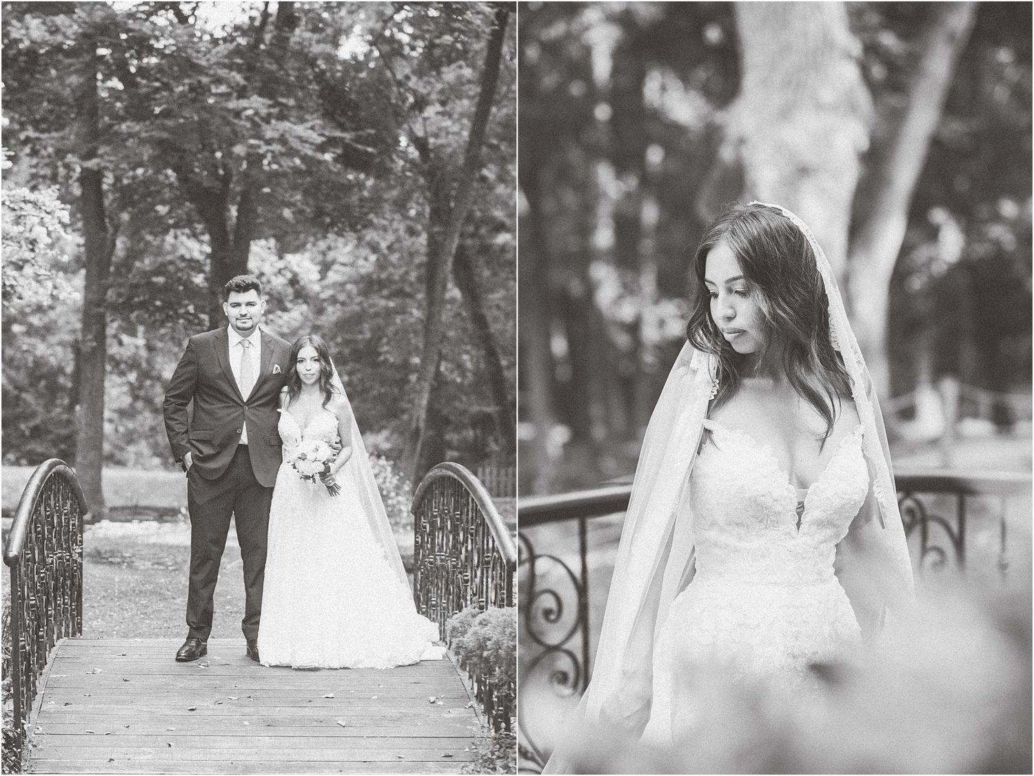 Classic black and white wedding photography of couple on rustic bridge surrounded by trees.