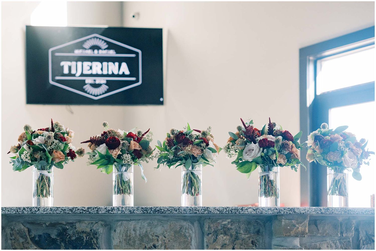Decorative floral arrangements with pink and purple blooms line the top of windows in a modern interior space.