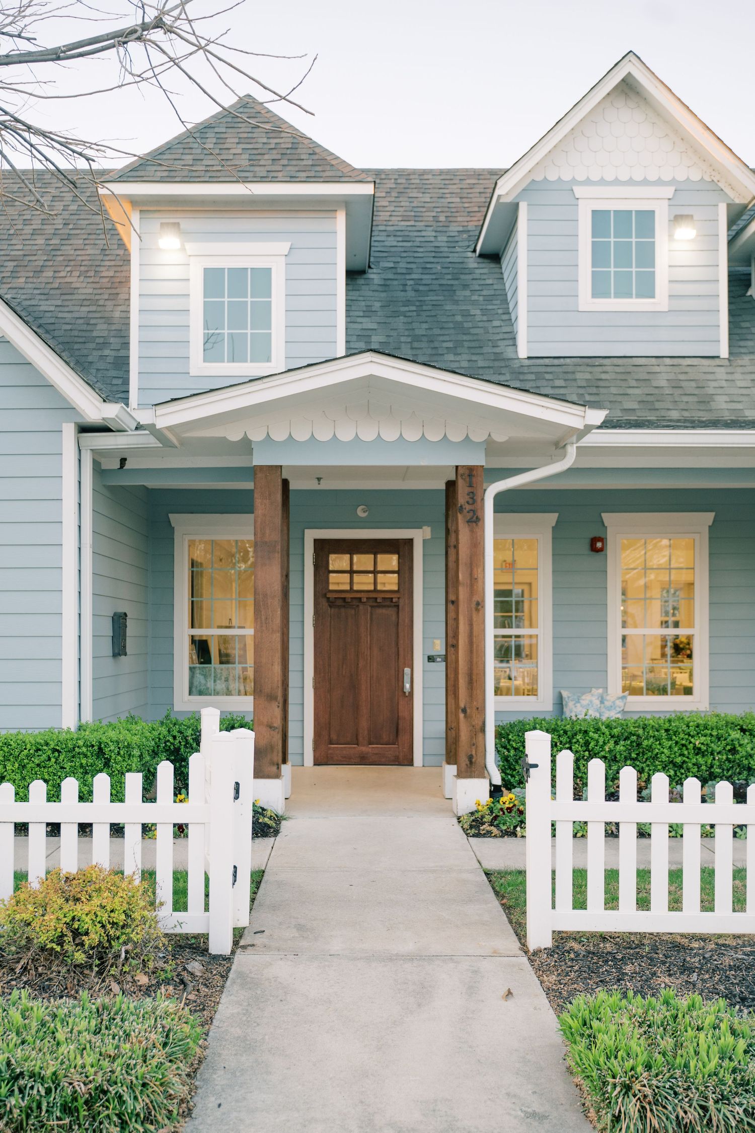 A series of exterior shots showing a modern craftsman style home with white picket fence and gray siding.