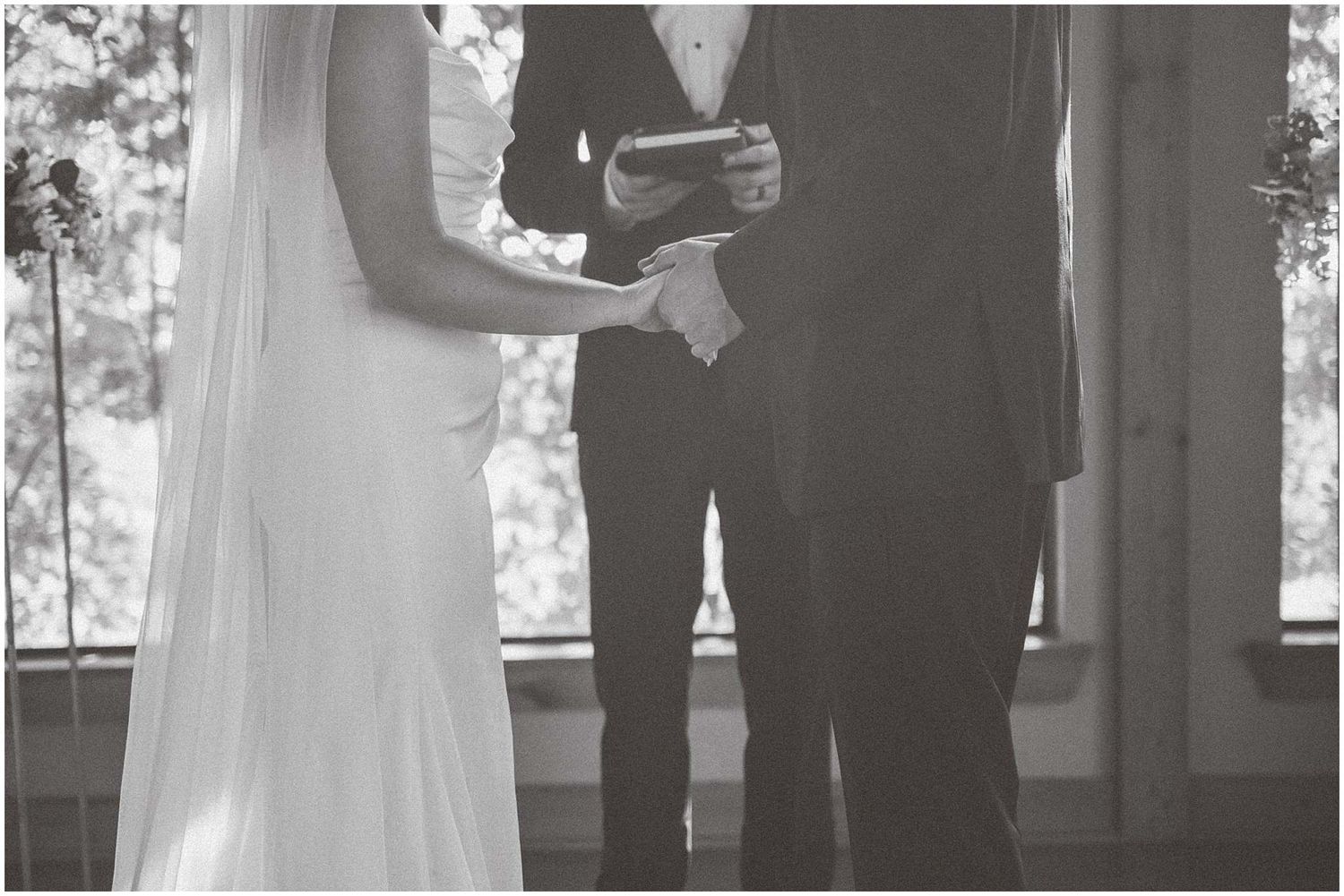 Black and white photo showing hands exchanging rings during an intimate wedding ceremony.