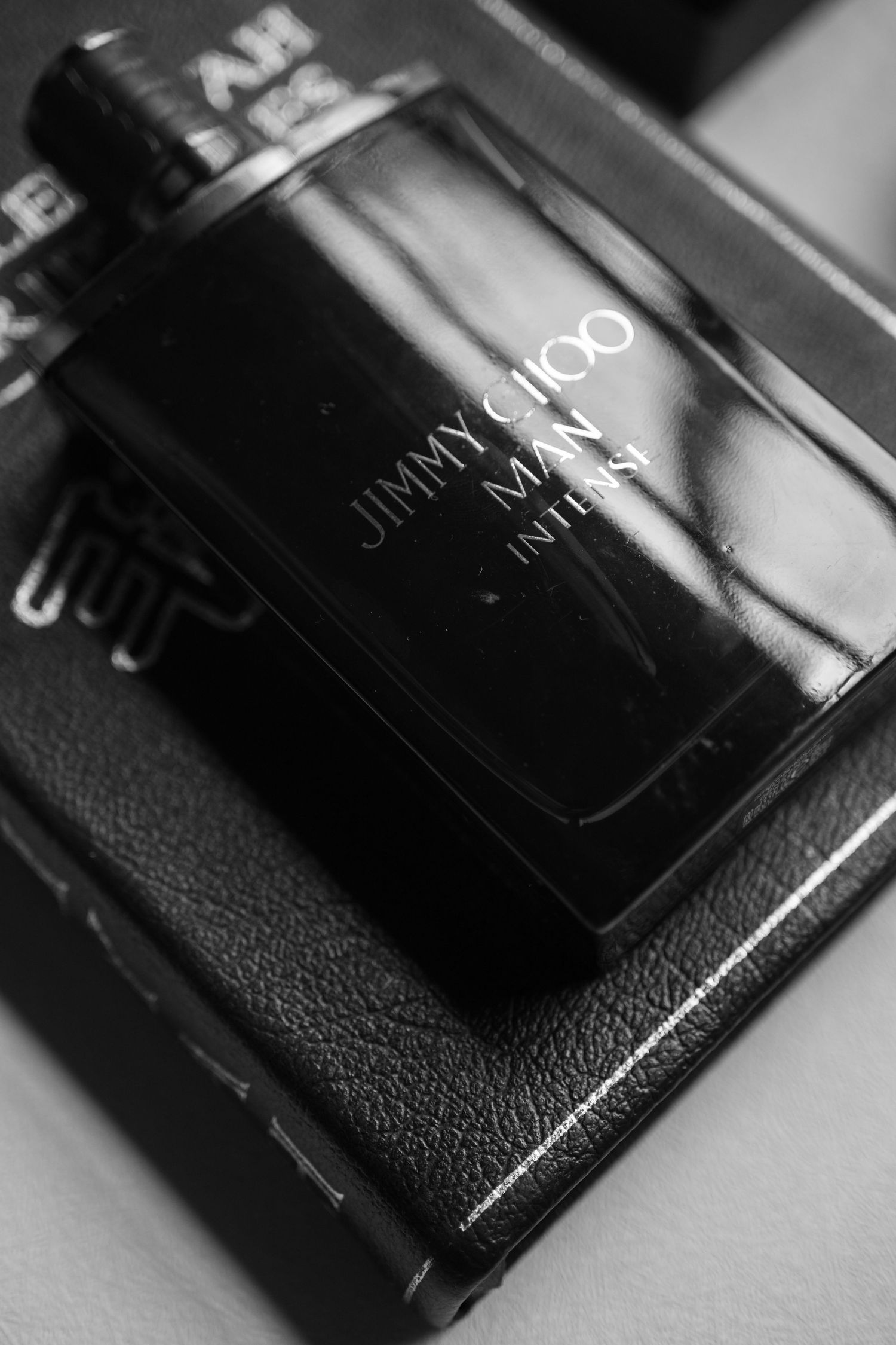 Black and white photo of Jimmy Choo Man Intense cologne bottle resting on its luxury gift box.