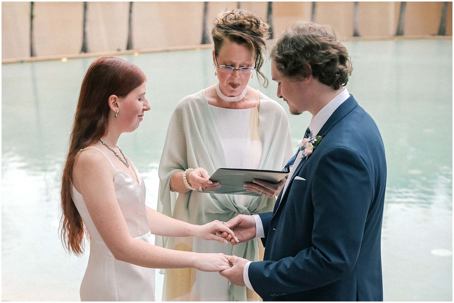 A romantic wedding ceremony moment by a waterfront with soft natural lighting.