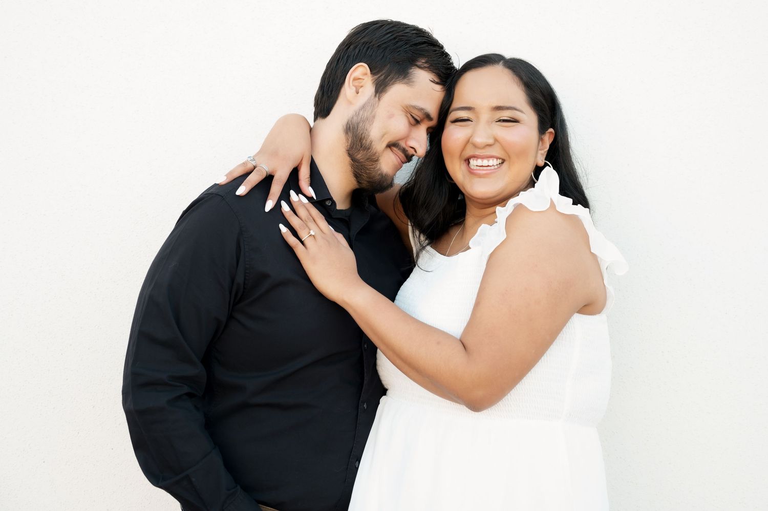 Couple in black and white outfits sharing an intimate moment against a white background.