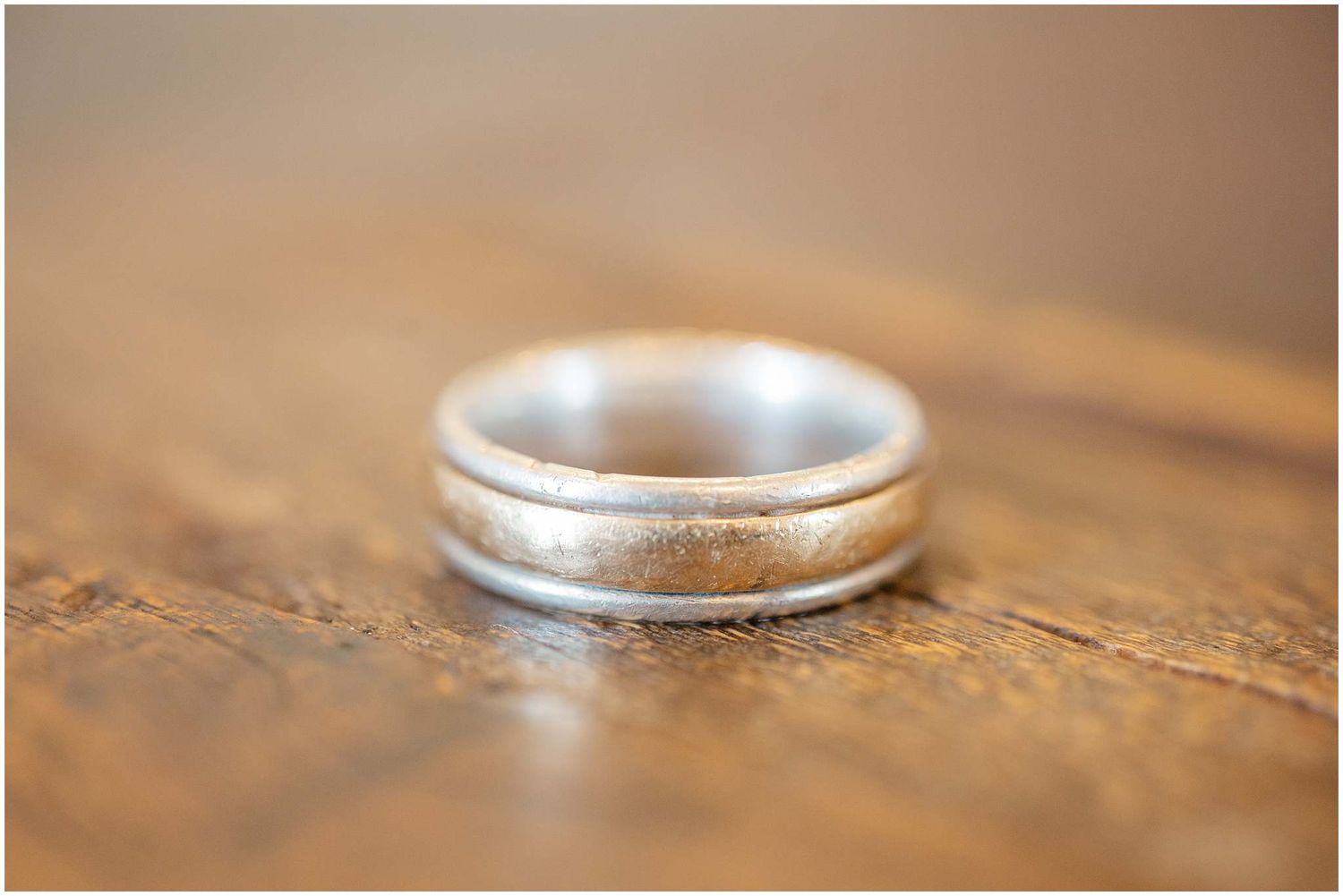Close-up macro shot of silver wedding rings on wooden surface with shallow depth of field.