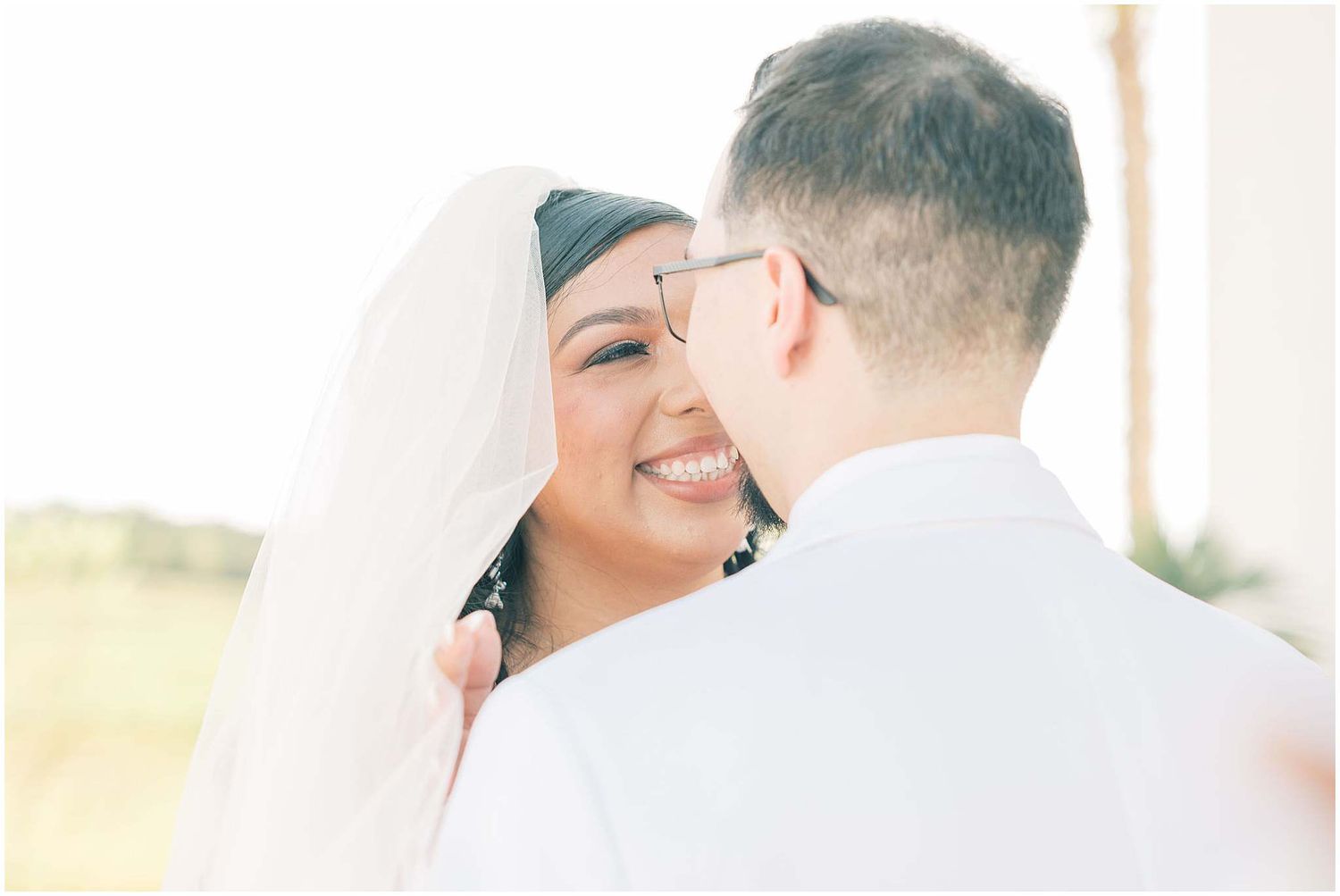 Romantic wedding portraits in soft natural light against white walls.