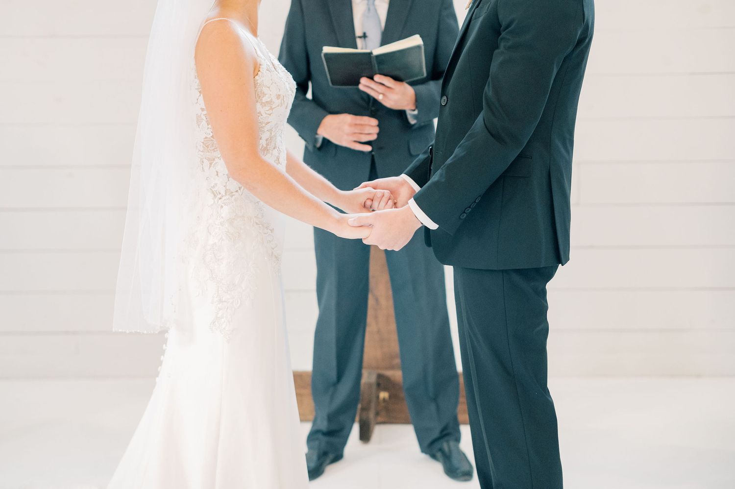 A couple shares an intimate moment during their wedding ceremony in a bright white church setting.