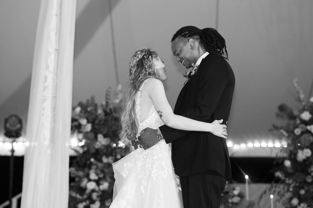 Bride and groom share an intimate first dance moment under a tent at their wedding reception.