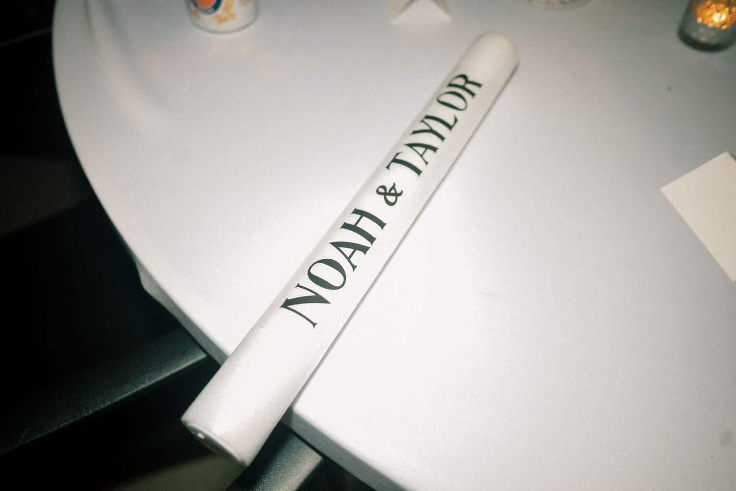 White rolled napkin printed with Noah and Taylor wedding couple names on a white tablecloth.