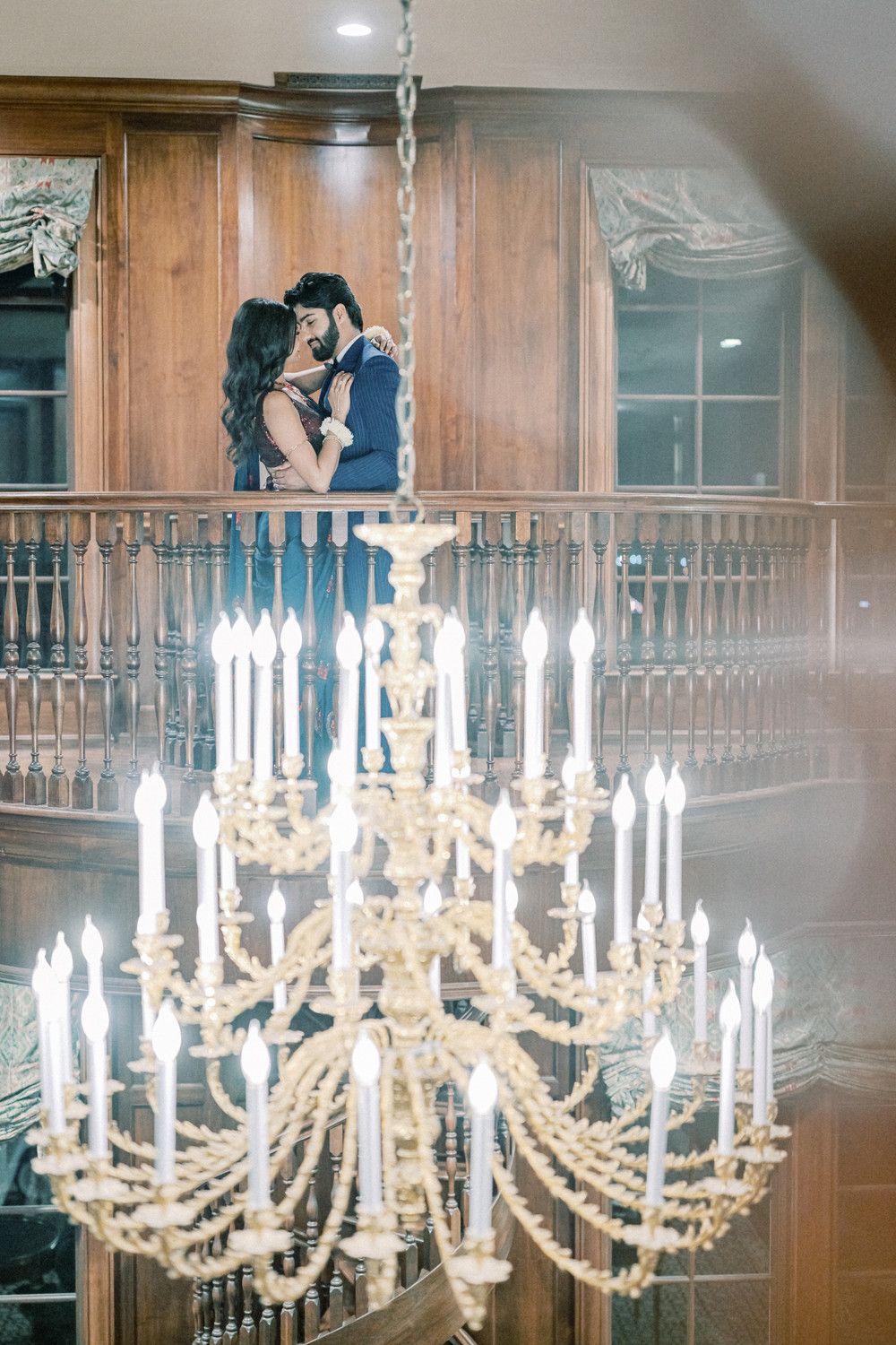 Crystal chandeliers illuminate a grand wood-paneled ballroom with elegant decor.