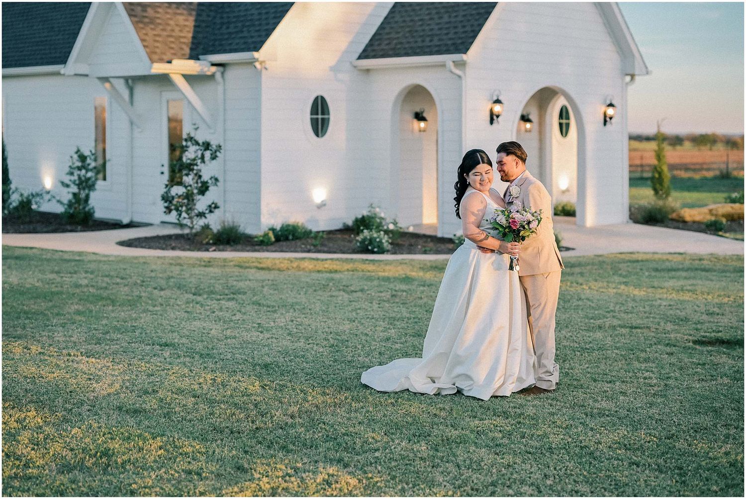White chapel wedding venue with arched windows and outdoor lighting at dusk.