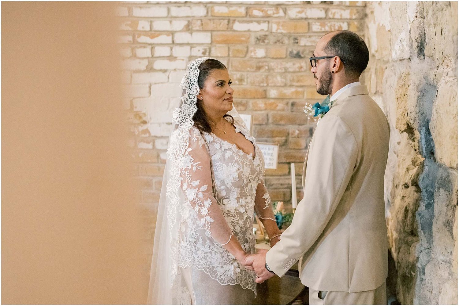 Romantic wedding ceremony moments against a backdrop of weathered brick walls and warm lighting.
