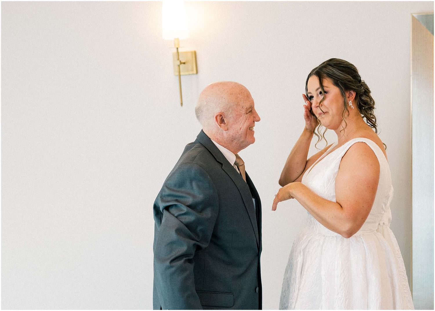 Candid wedding first look moments captured in a minimalist white room.
