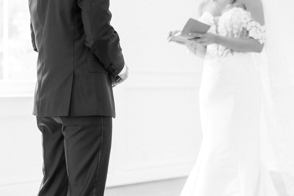 Black and white photo of bride reading vows to groom during elegant wedding ceremony.