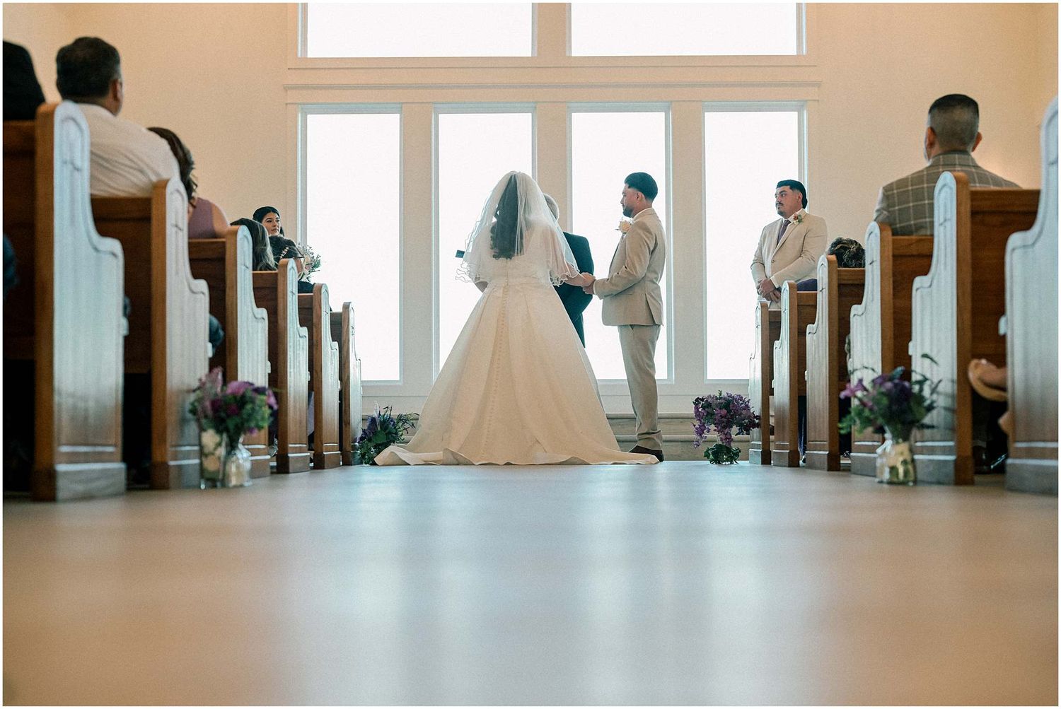 Wide angle view of church interior during wedding ceremony with natural lighting.