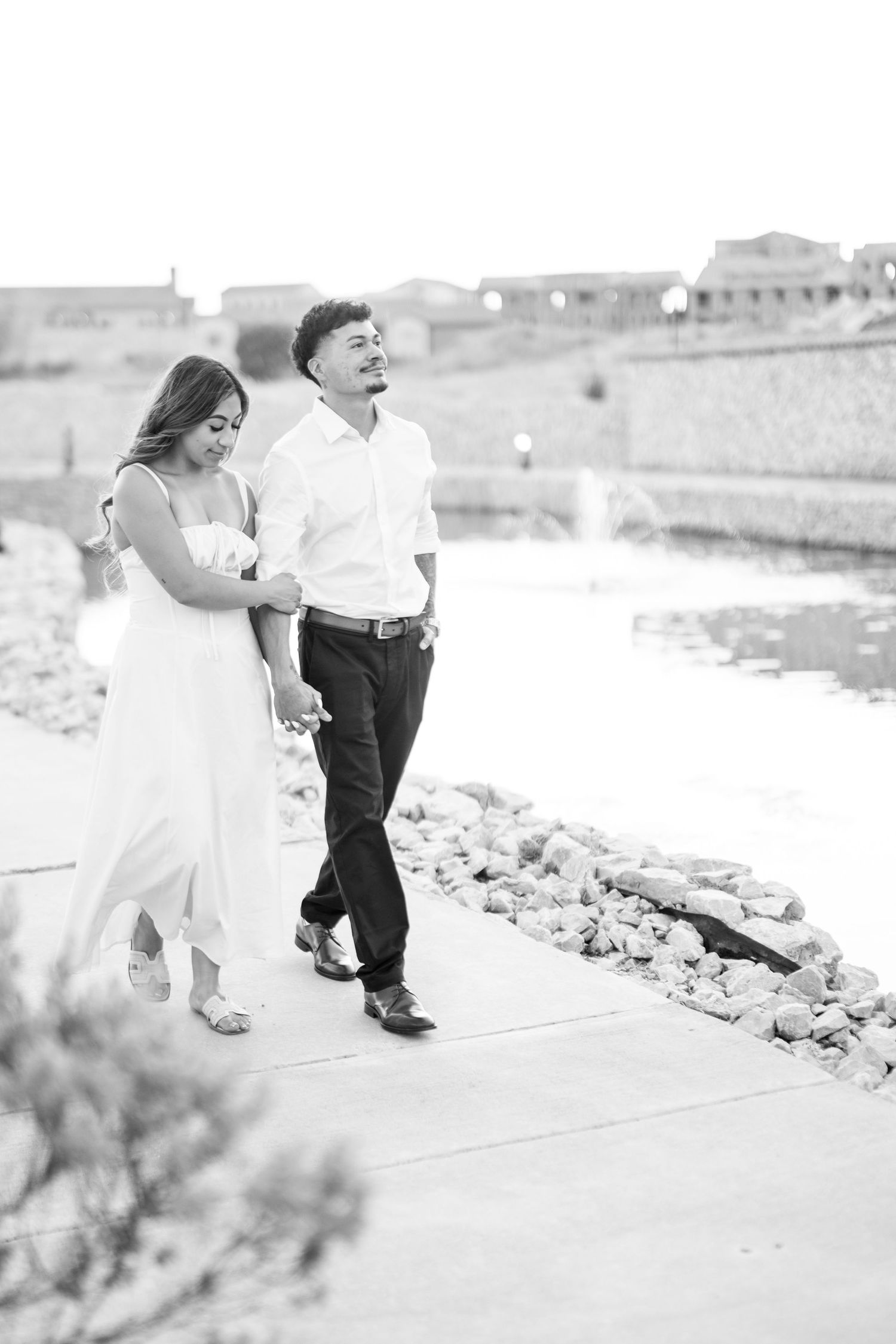 Black and white photo of couple walking and laughing together along a stone waterway path.