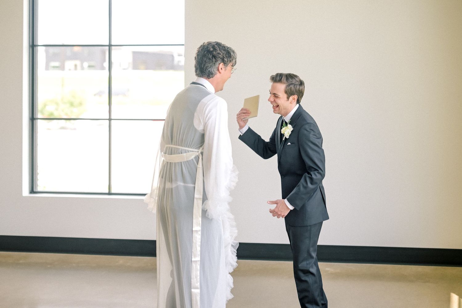 Groom sharing vows with officiant before wedding ceremony in bright modern venue.