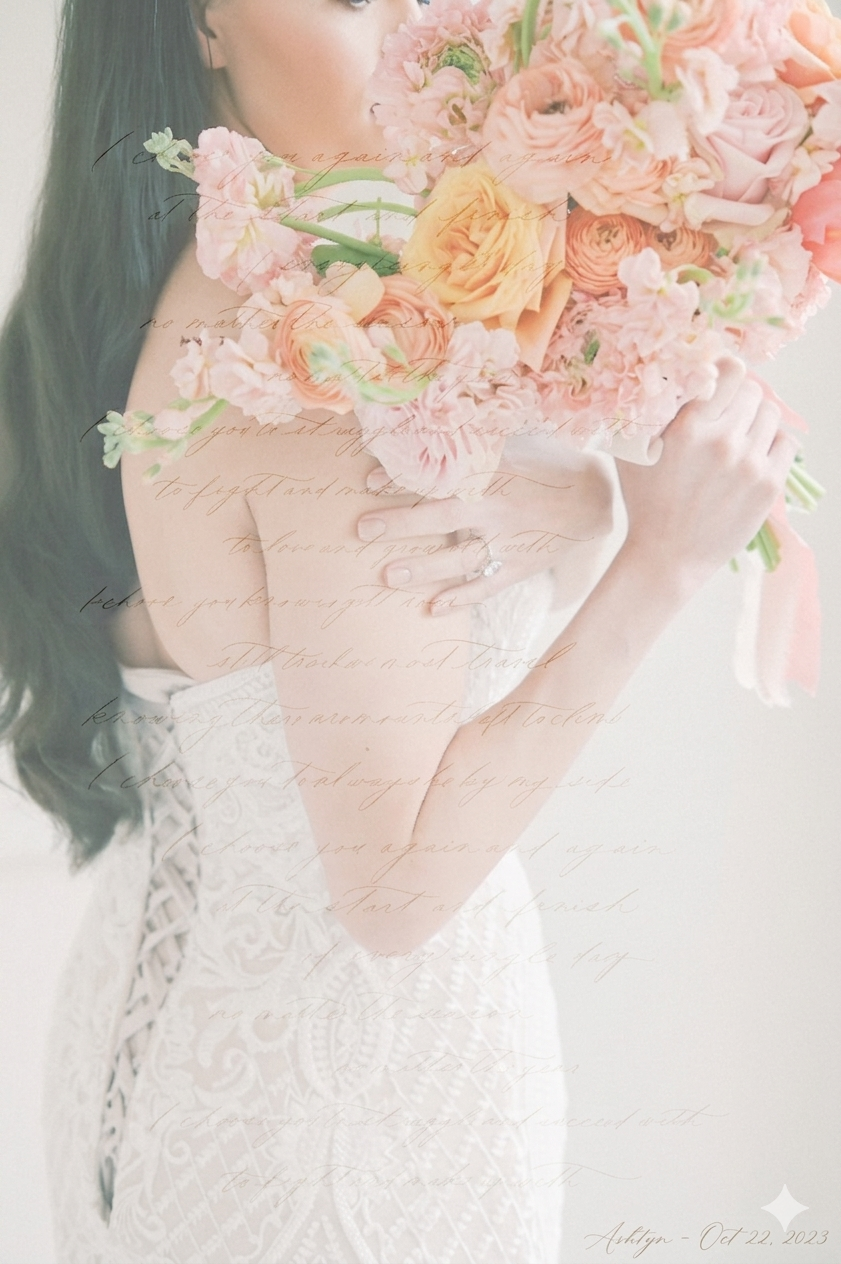 Bride in lace gown holding lush peach and pink floral bouquet with roses and ranunculus on light background.