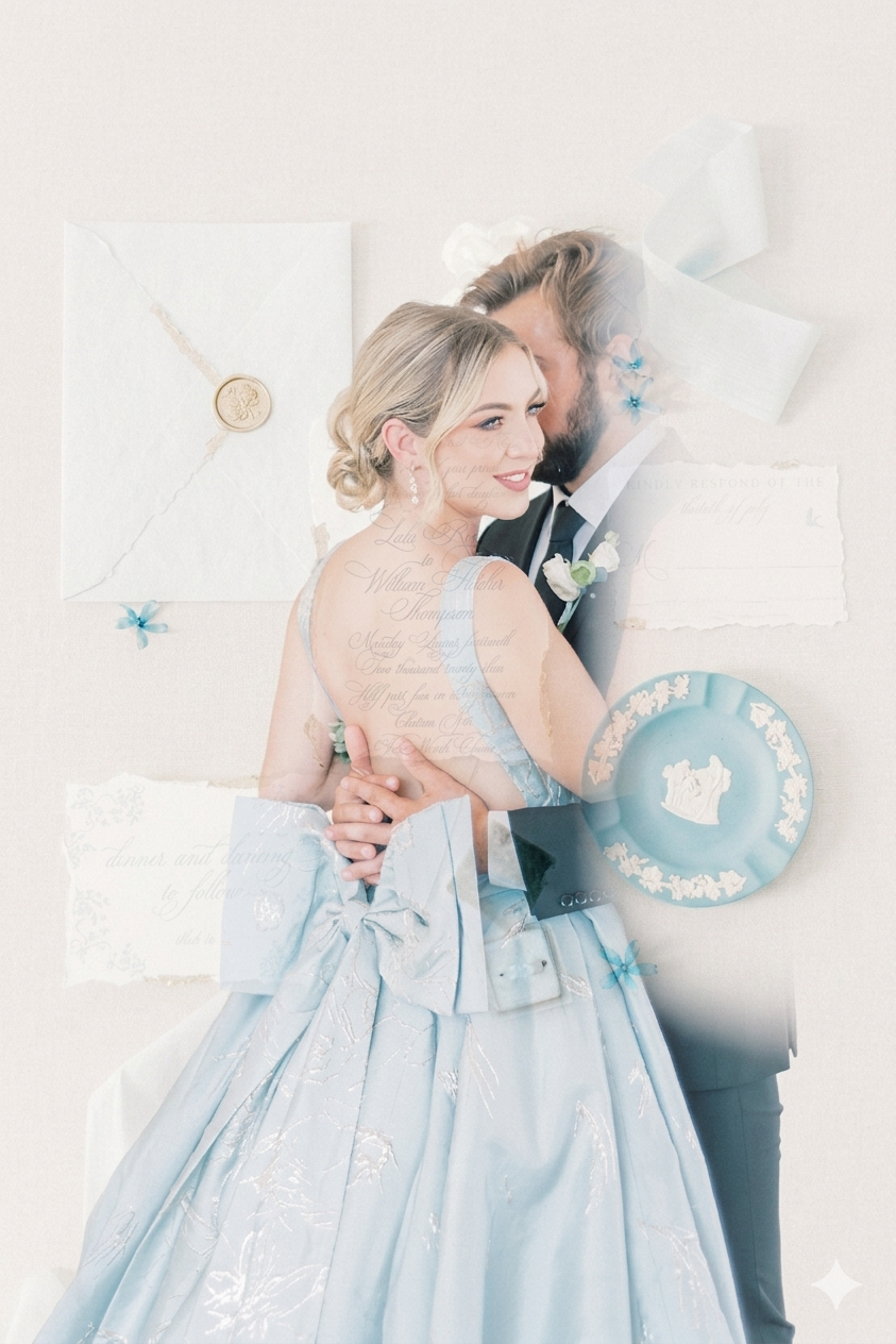Bride in blue gown embraced by groom, surrounded by elegant wedding stationery in soft pastel tones.