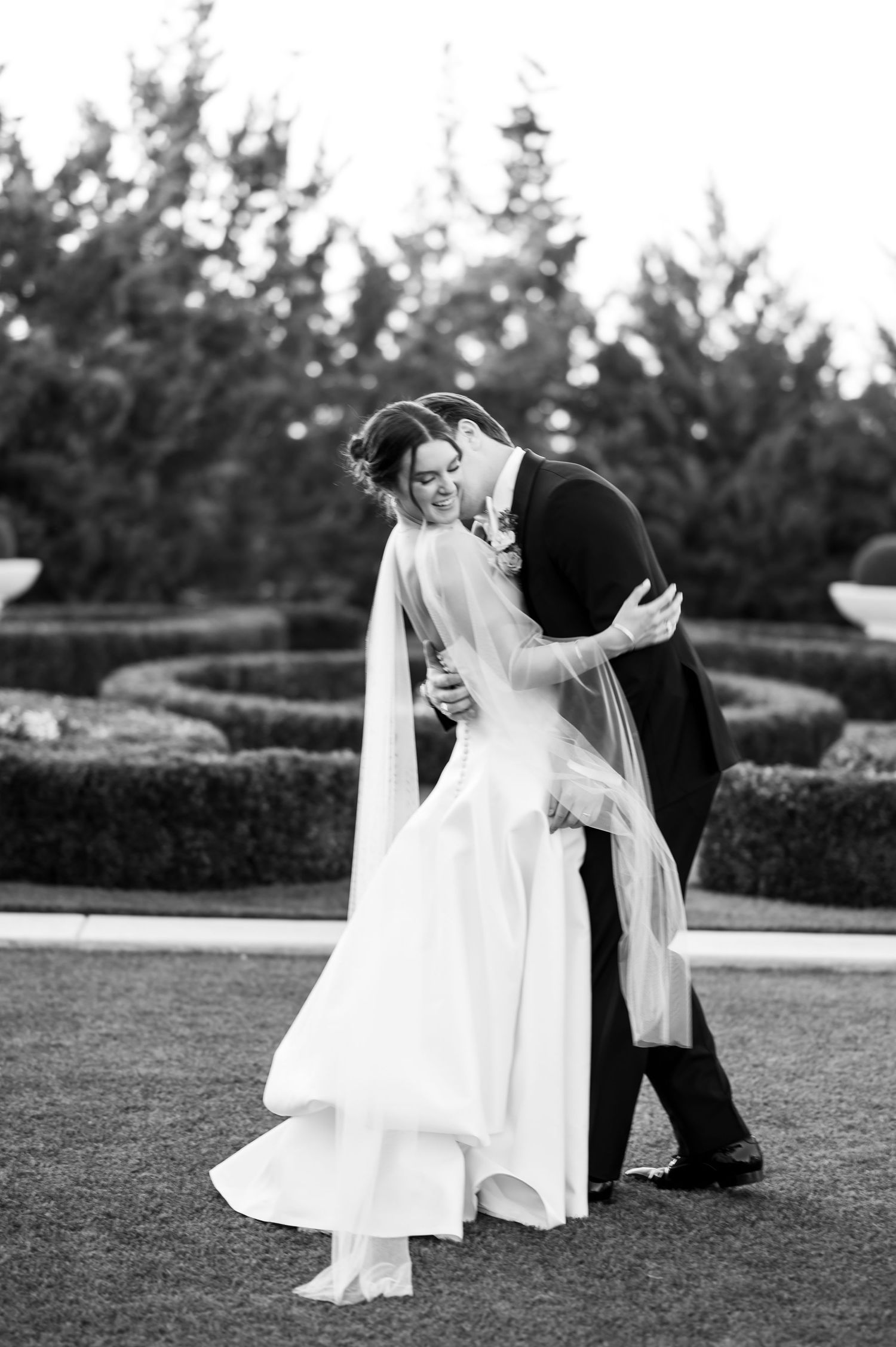 Black and white photos of wedding couple dancing together on manicured lawn.