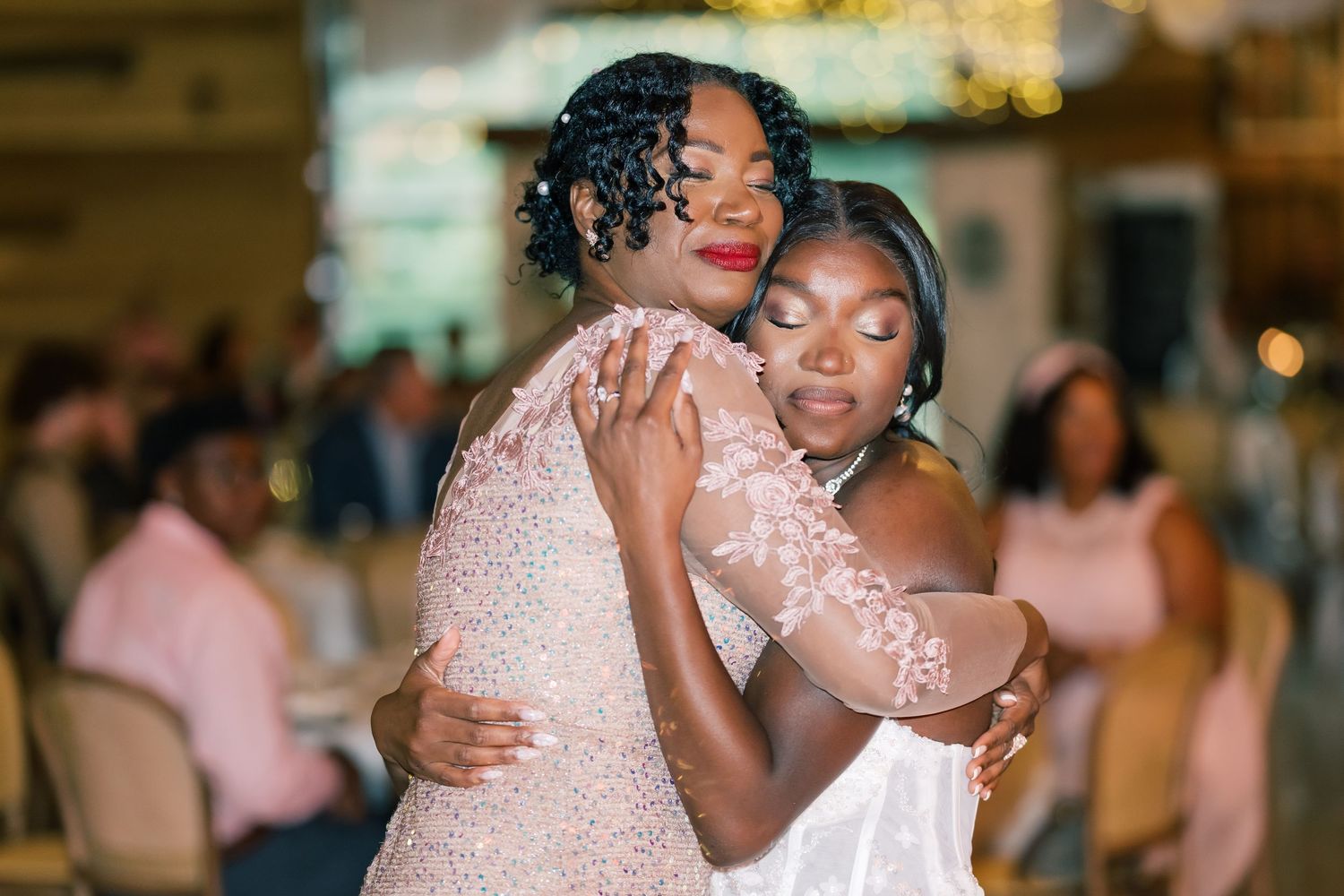 Bride and mother share emotional embrace during special dance at elegant wedding reception.
