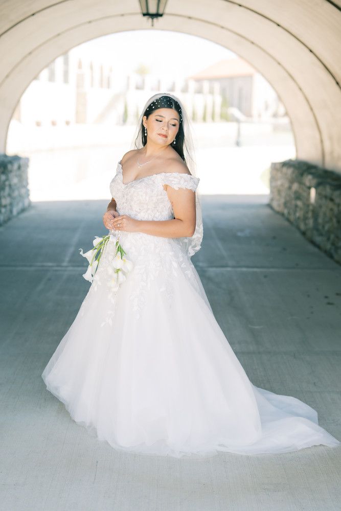 A bride in a flowing white ballgown twirls under a stone archway in a series of romantic wedding photos.