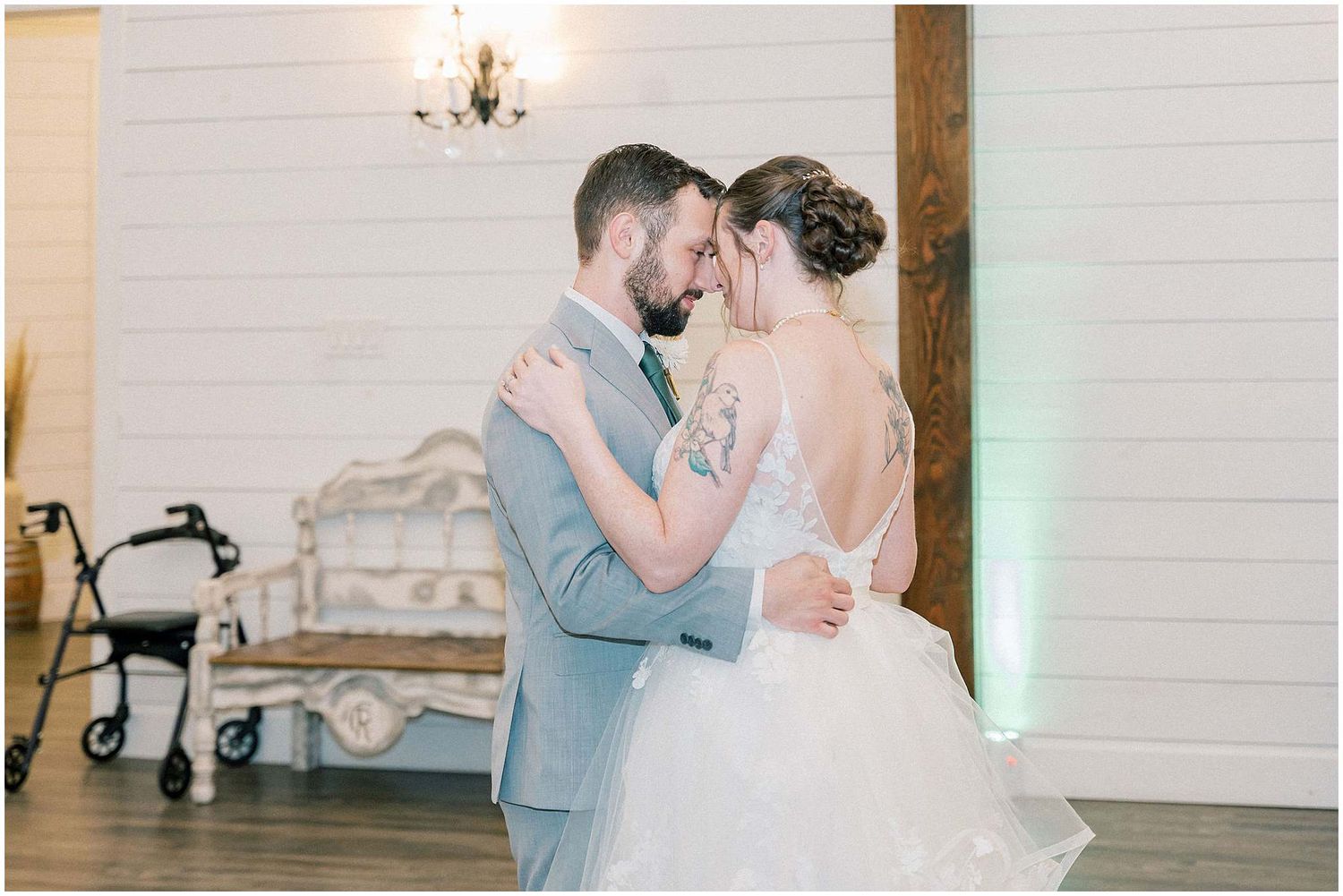 Romantic first dance moment between newlyweds at rustic barn wedding venue with white brick walls.