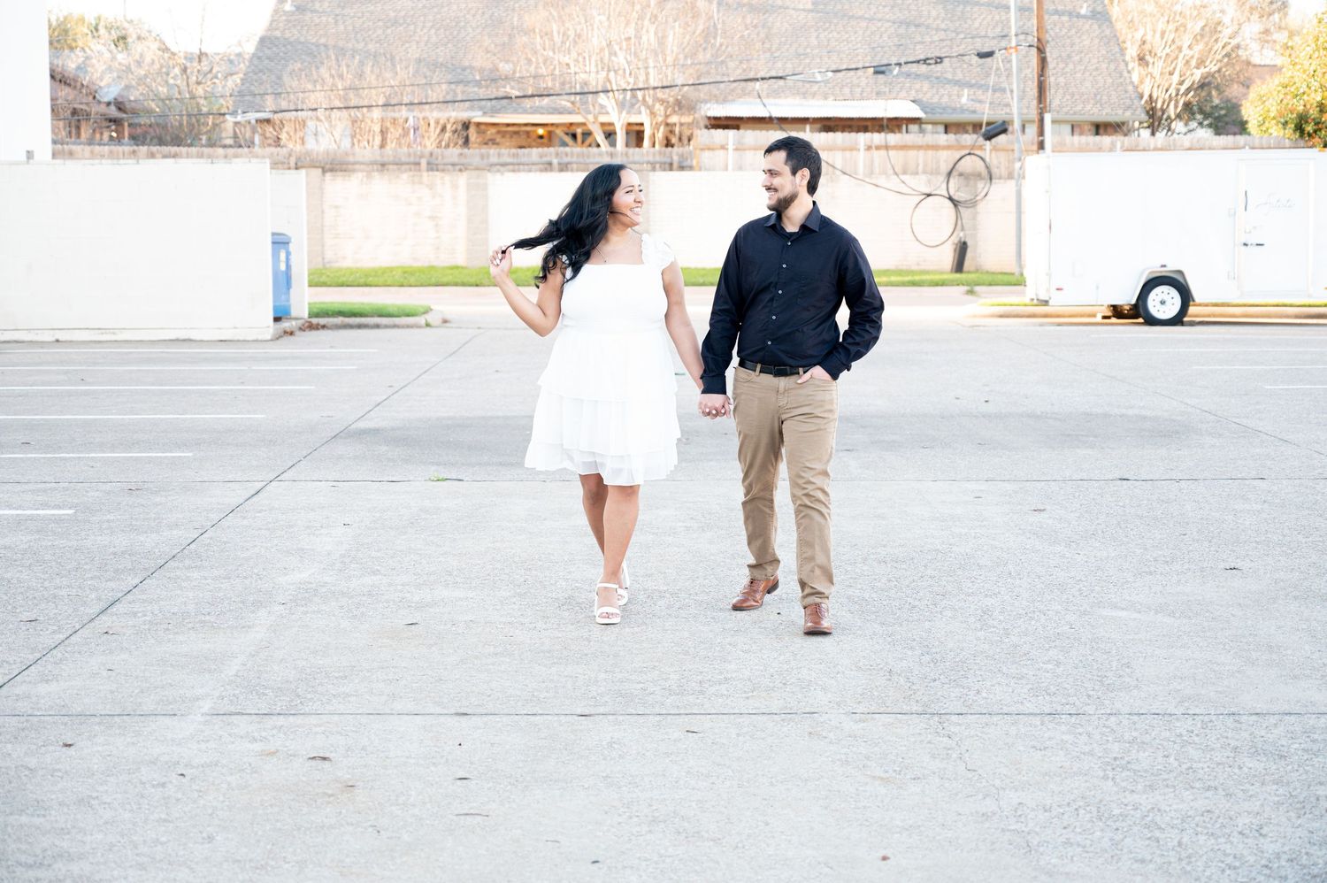 A couple in coordinated outfits walking together on a concrete surface with a building in the background.