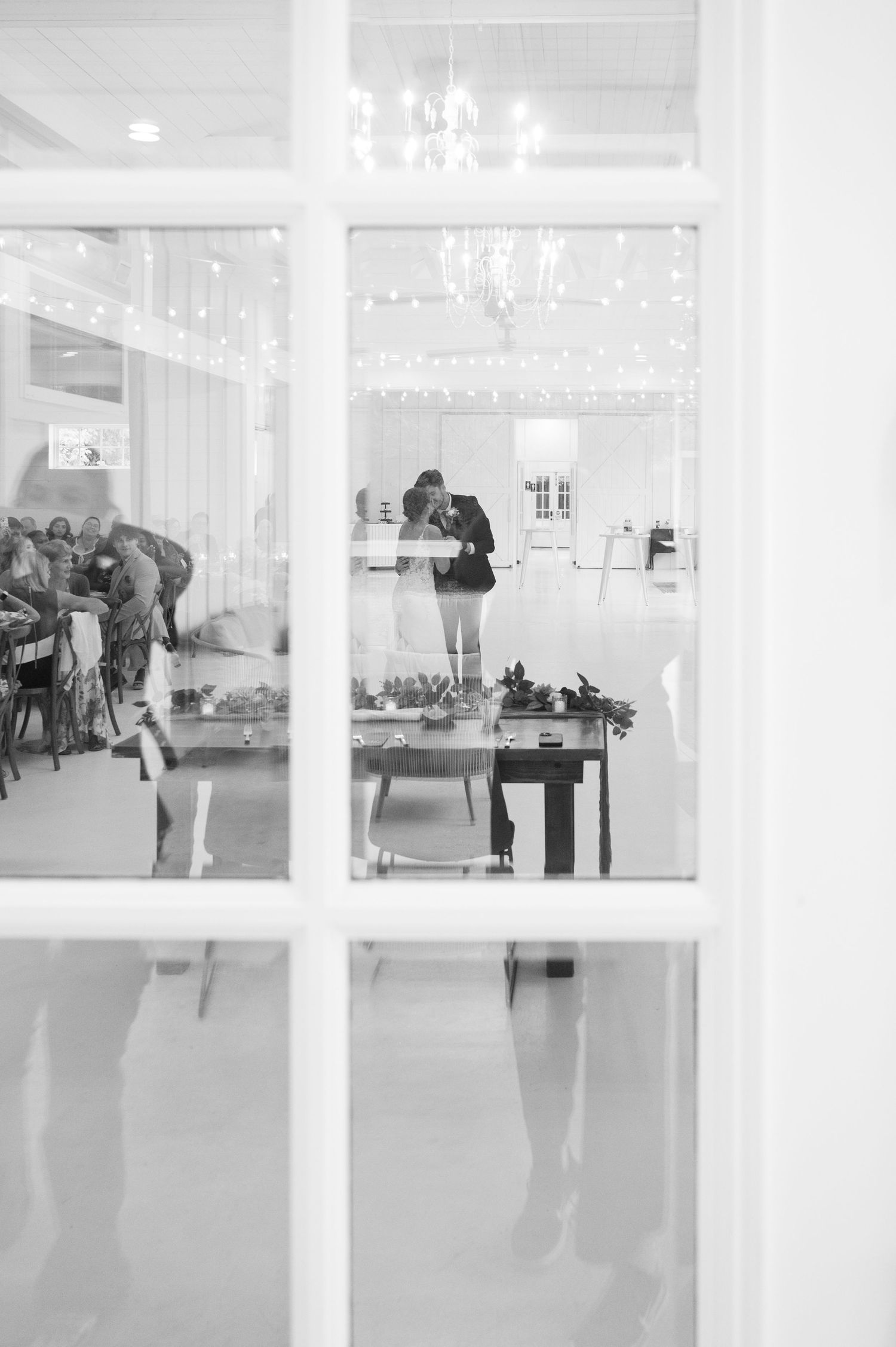 Modern white wedding venue interior with glass windows and elegant lighting fixtures.