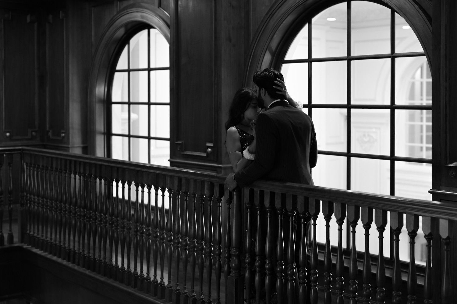 Dramatic black and white composition of arched windows and balcony silhouettes.