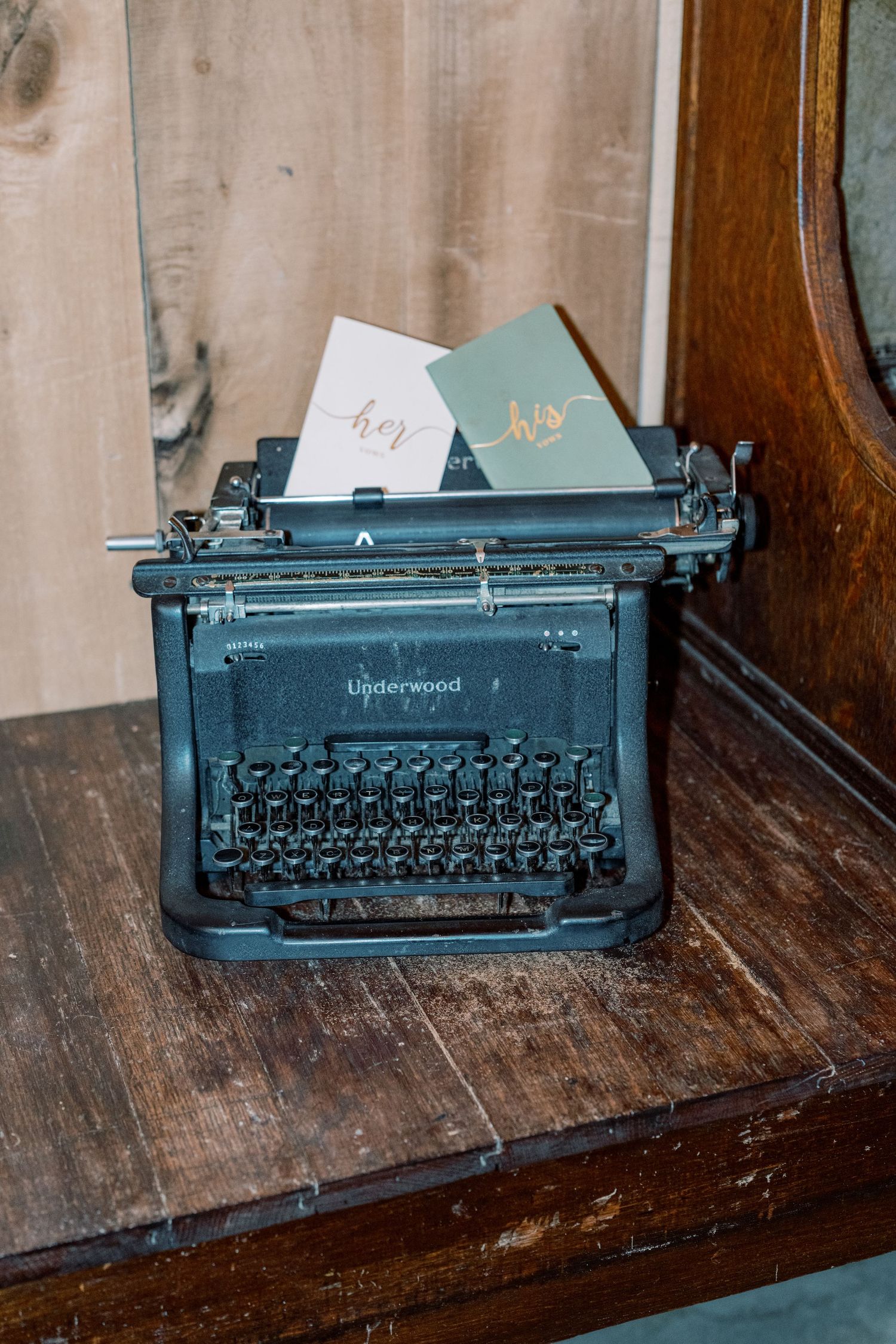 Vintage Underwood black typewriter with wedding place cards on rustic wooden furniture.