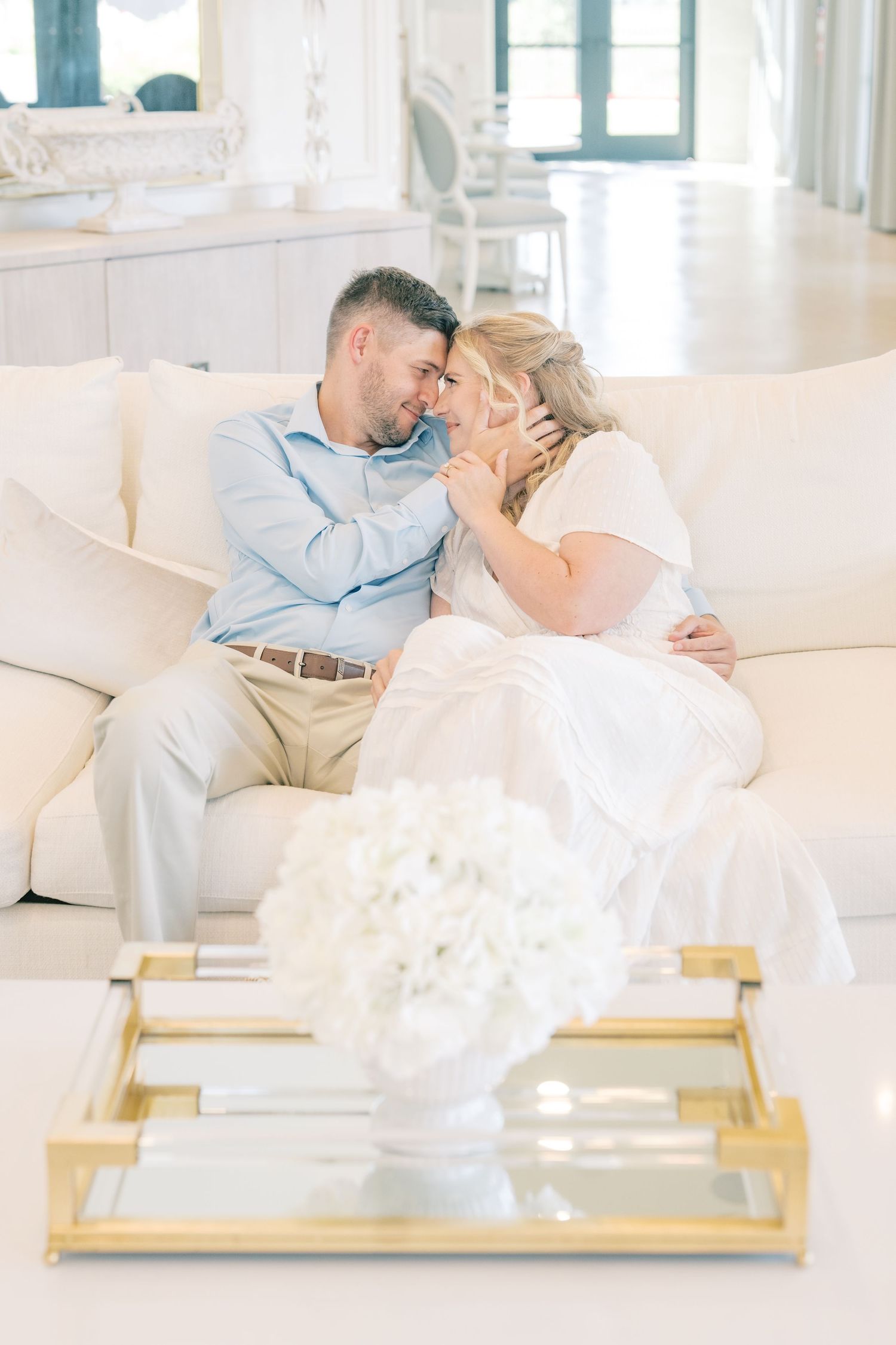 Couple sharing a romantic moment on a white sofa in an elegant bright living room.