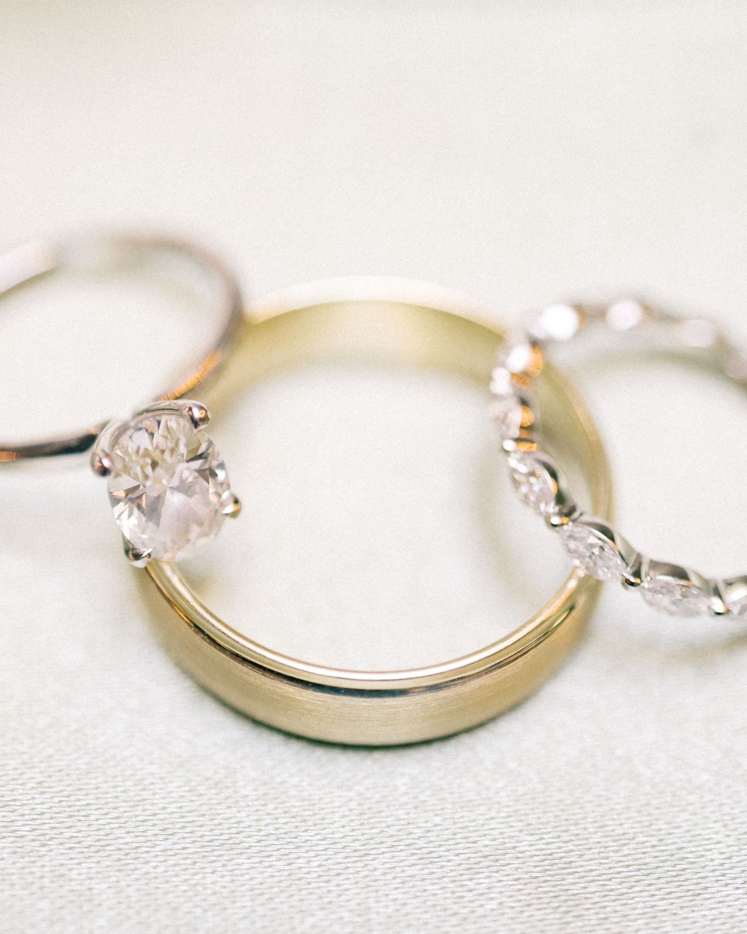 Three elegant wedding rings arranged together, featuring a solitaire diamond, gold band, and diamond eternity ring.