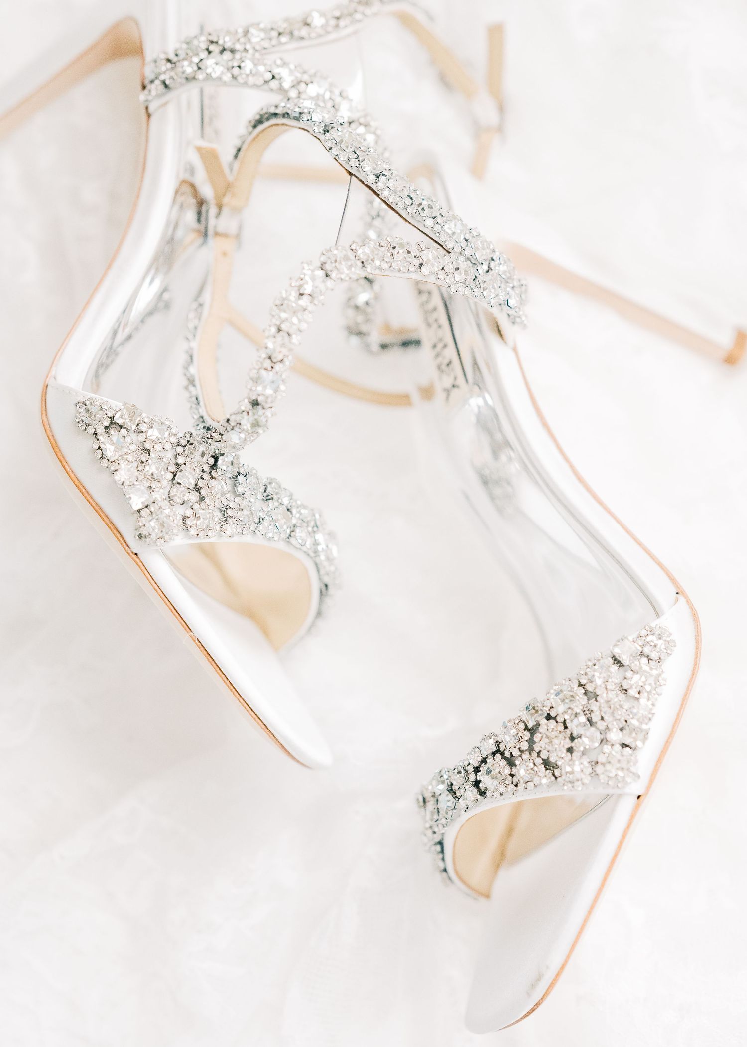 Elegant crystal-embellished bridal heels with clear straps and rhinestone details on a white background.
