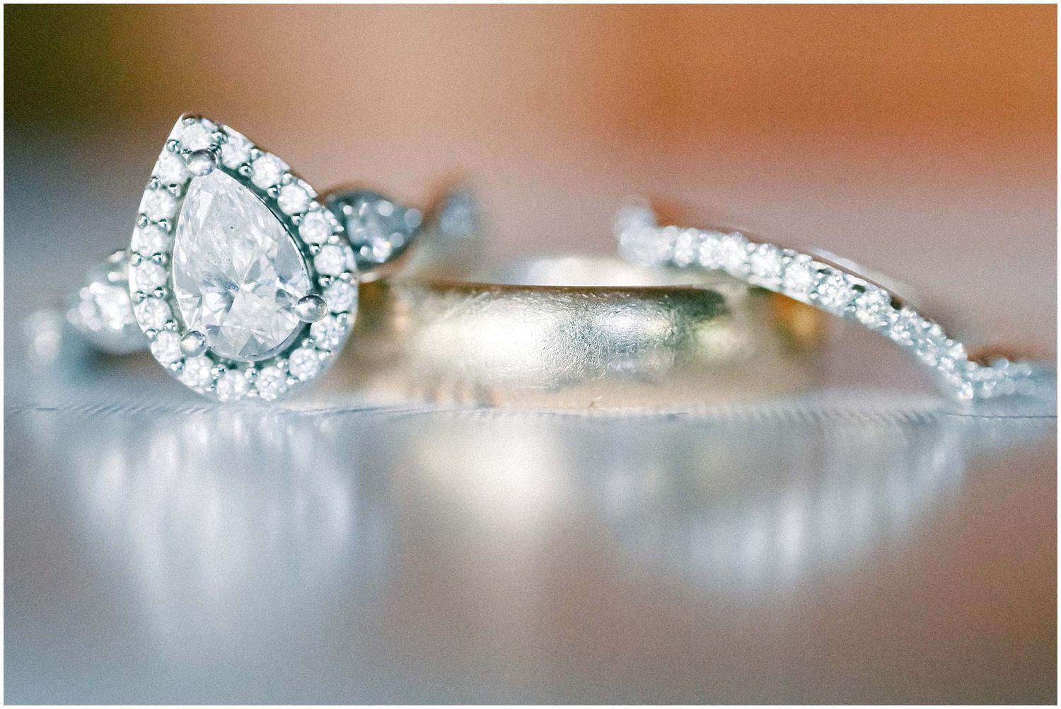 Close-up of a pear-shaped diamond engagement ring and wedding band with pavé diamonds.
