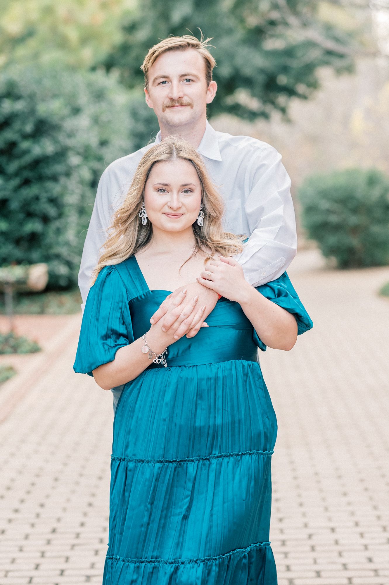 A couple in a romantic outdoor photoshoot with a person wearing a teal tiered maxi dress and white shirt.