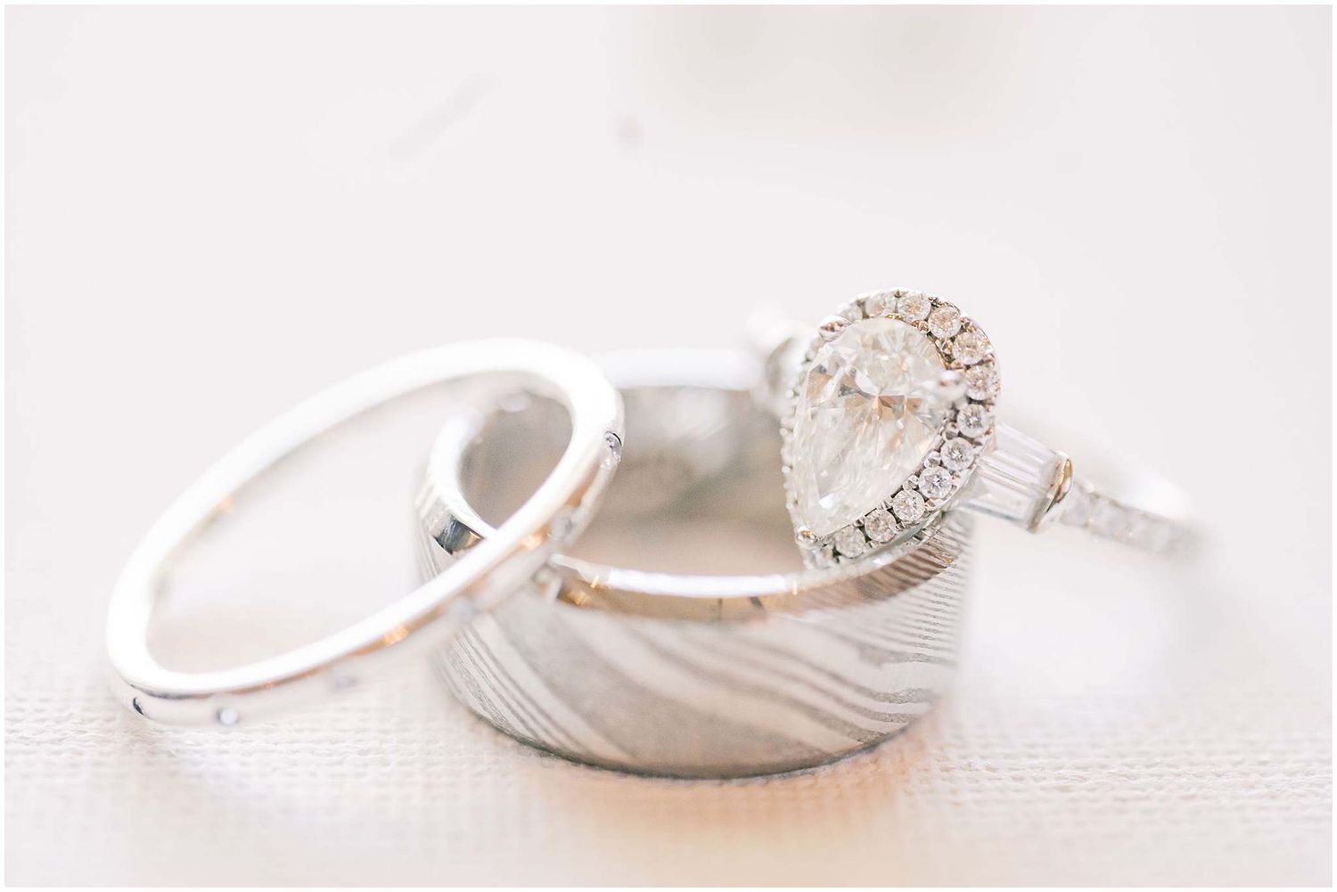 Elegant wedding rings and jewelry arranged artistically on a light textured surface.