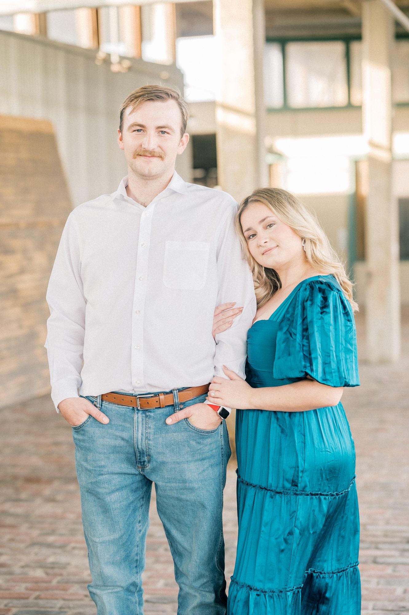 Romantic couple in casual attire share tender moments in a rustic indoor setting with natural lighting.